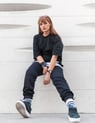 woman in black long sleeve shirt and blue denim jeans sitting on white concrete wall