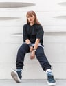 woman in black long sleeve shirt and blue denim jeans sitting on white concrete wall