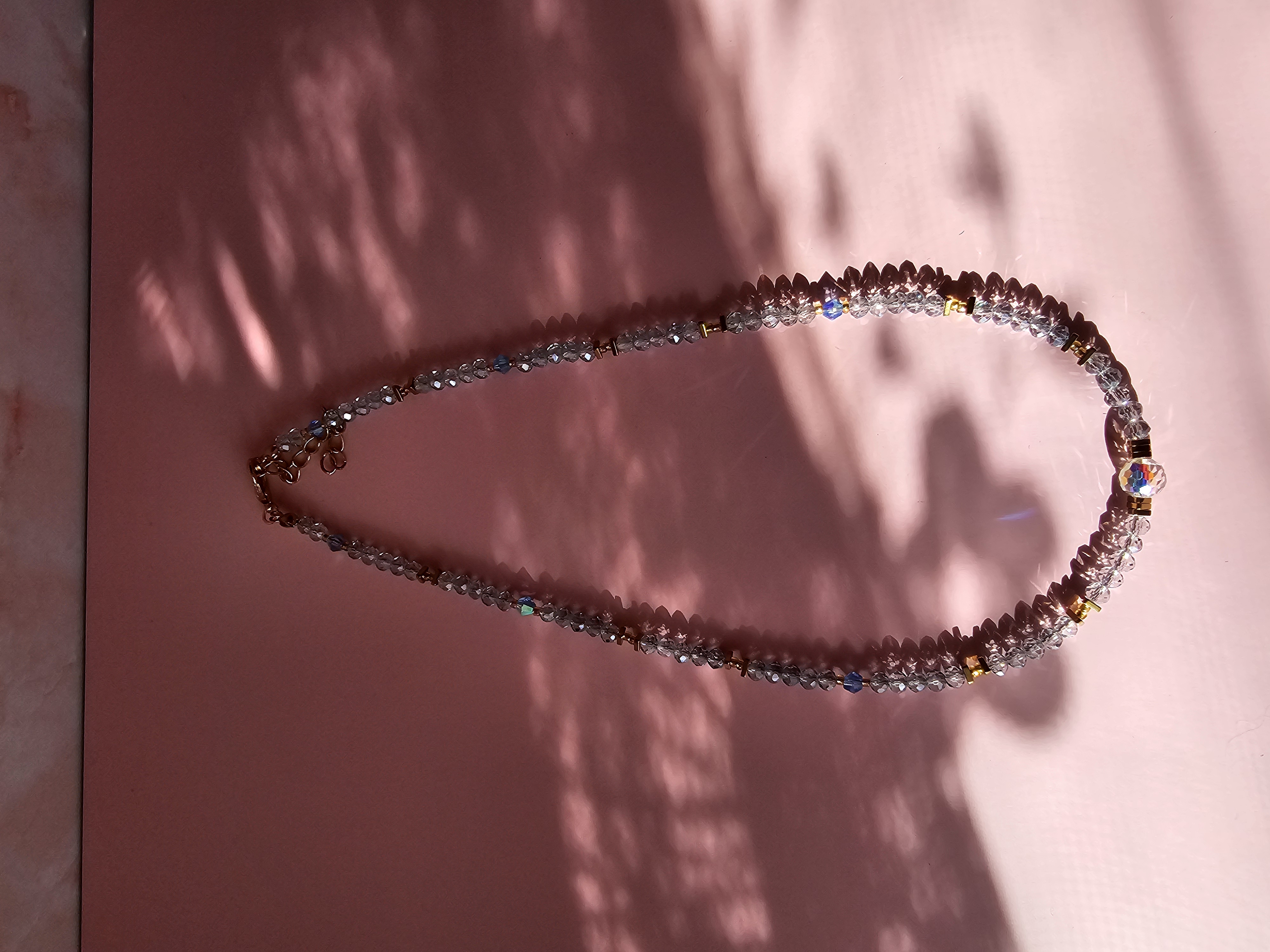 Puošnus skaidrios spalvos kaklo vėrinys su karoliuku