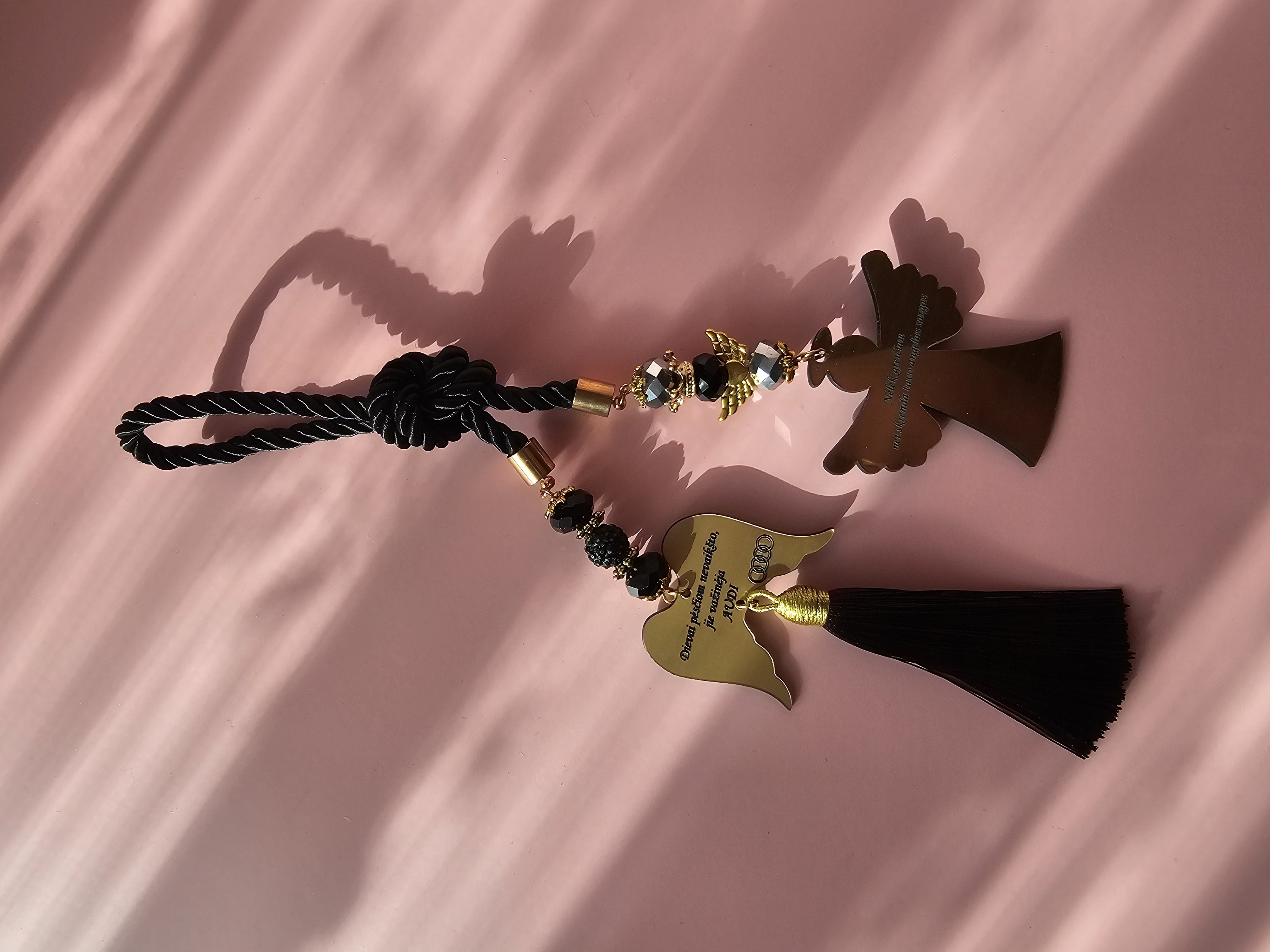 Automobilio pakabukas su užrašu "Nelėk greičiau nei skrenda tavo angelas sargas" ir Audi