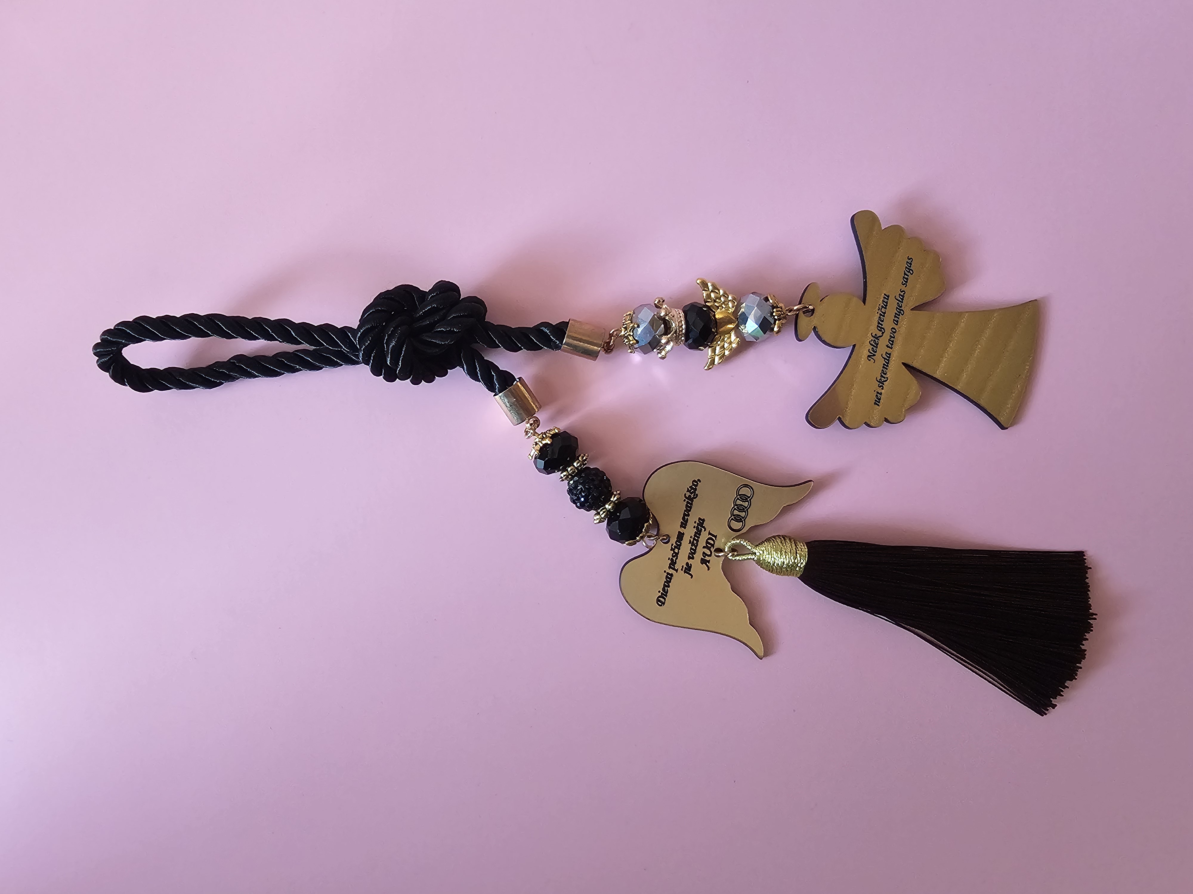 Automobilio pakabukas su užrašu "Nelėk greičiau nei skrenda tavo angelas sargas" ir Audi