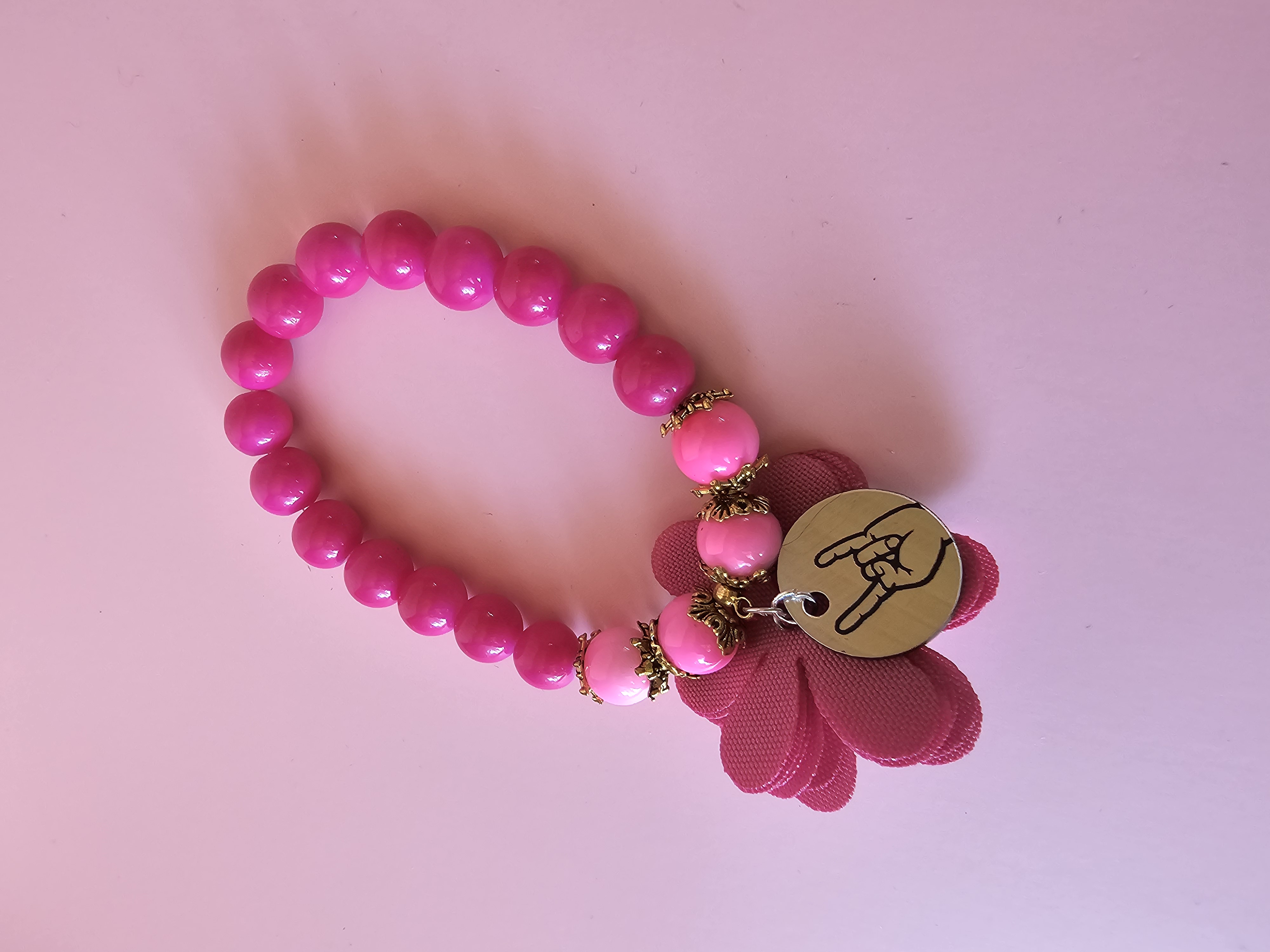 Rožinė apyrankė su ženklu