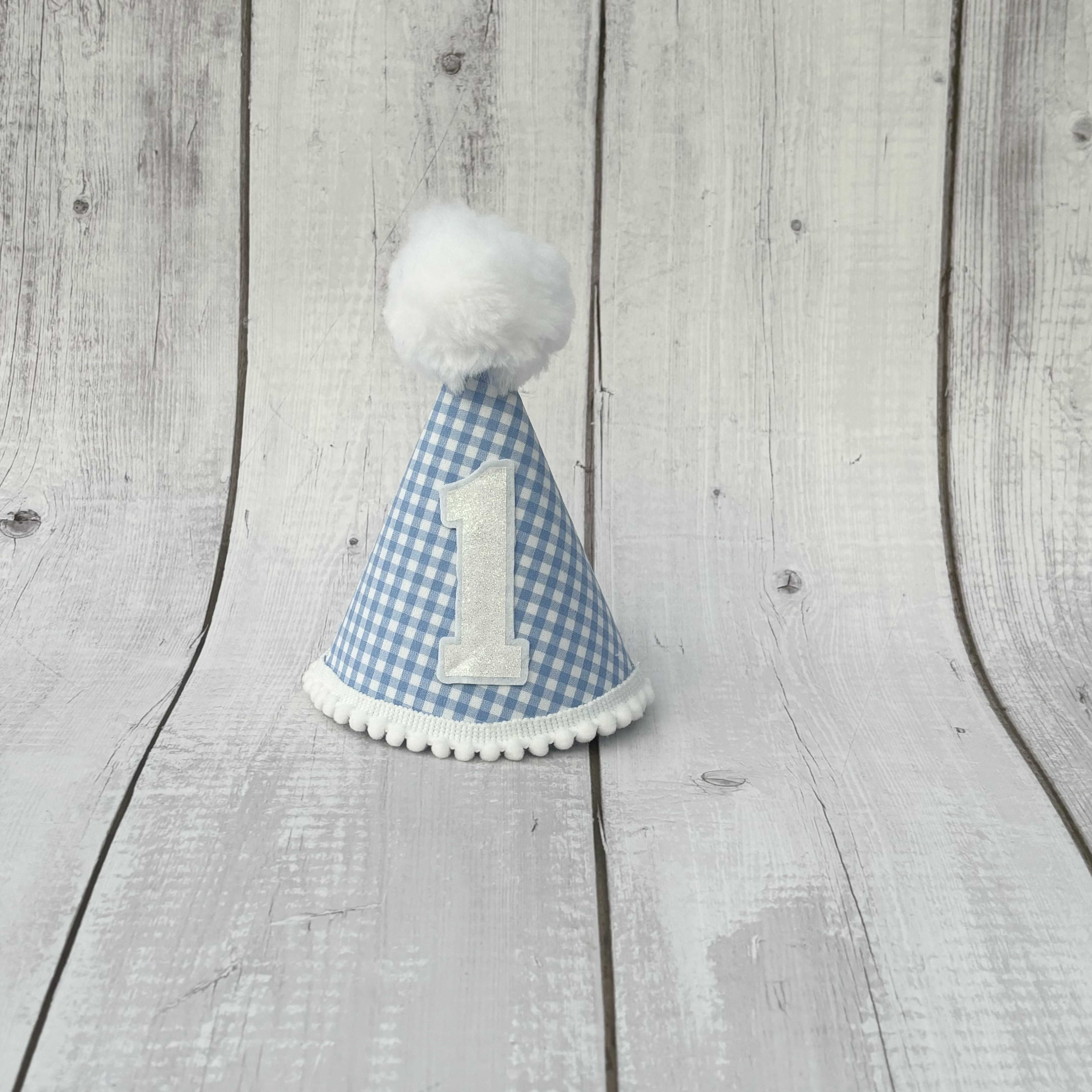 Light blue gingham child's party hat with white trims and pom pom