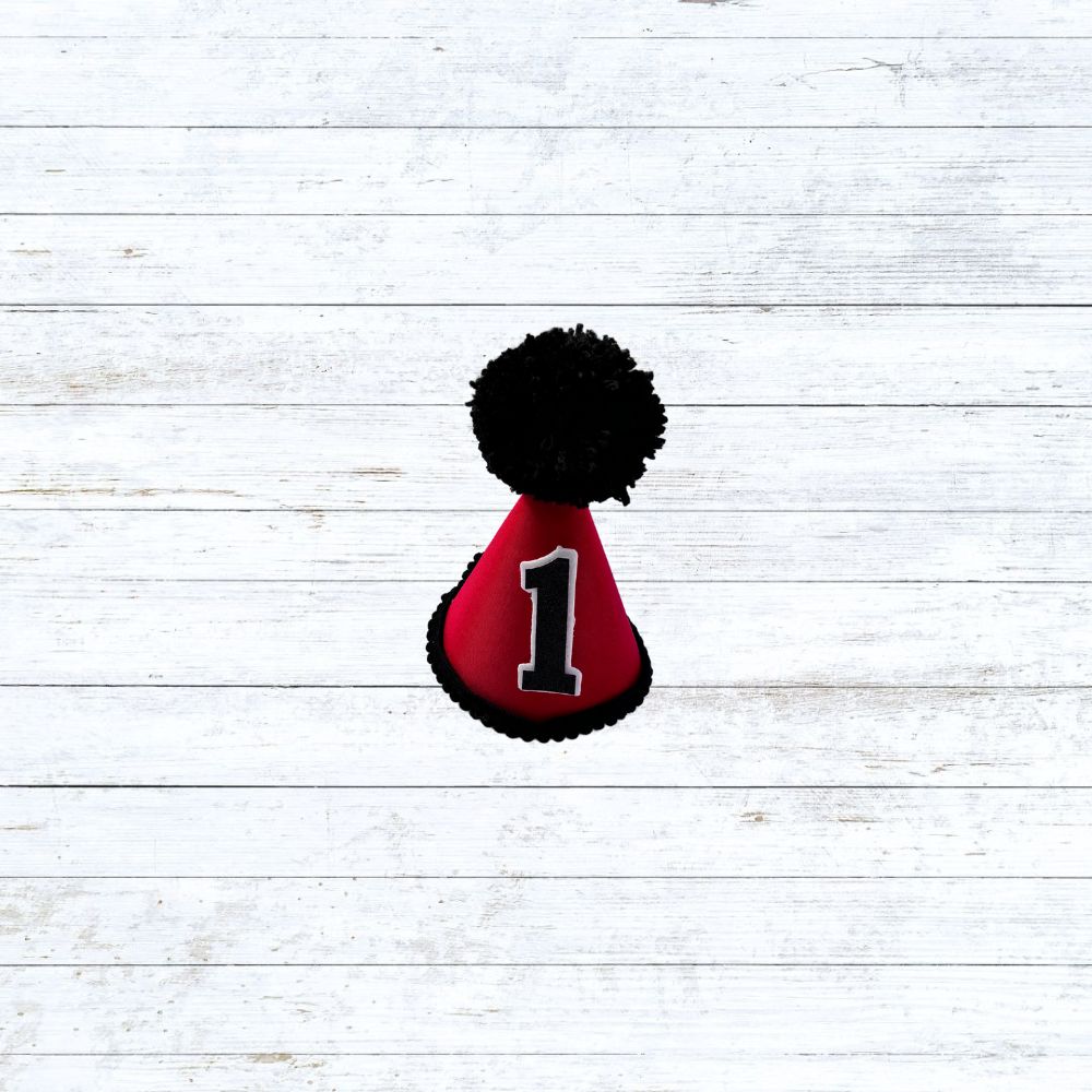 Red child's party hat with black trims and pom pom