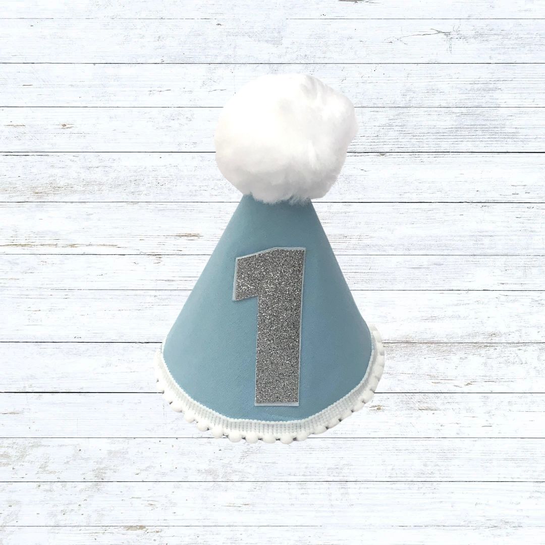 Light blue child's party hat with white trims and pom pom