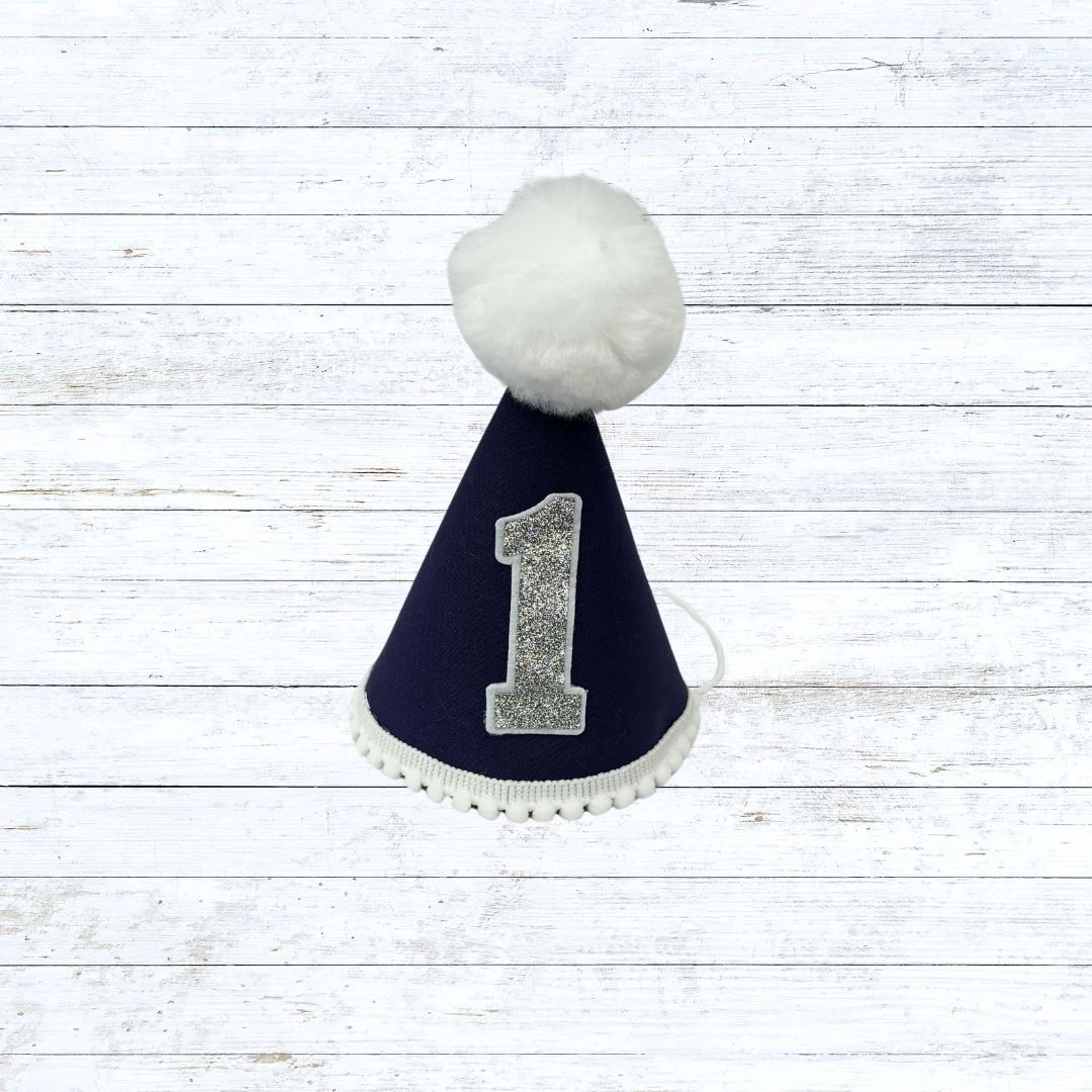 Navy blue child's party hat with white trims and pom pom