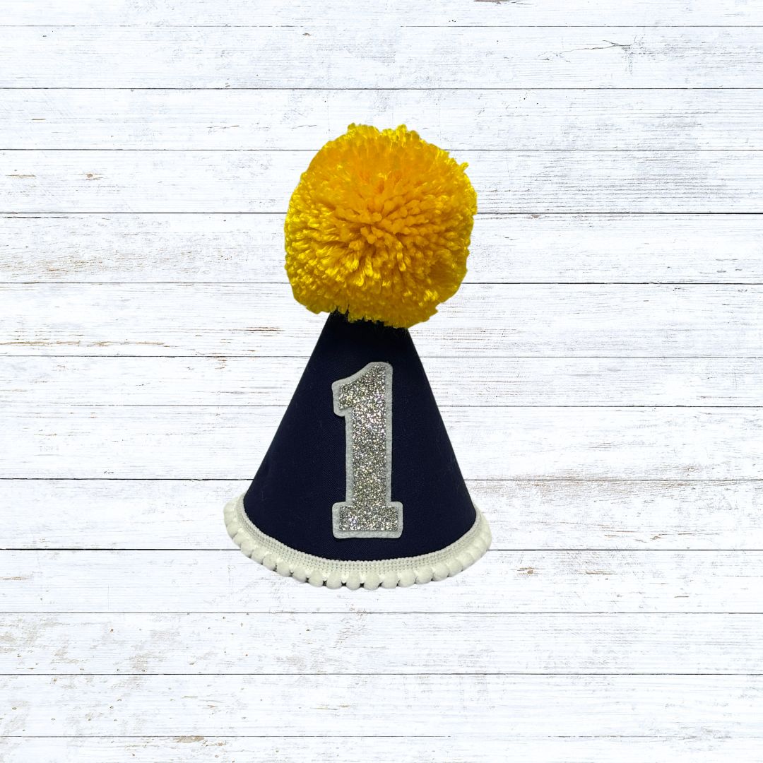 Navy blue child's party hat with white trims and pom pom