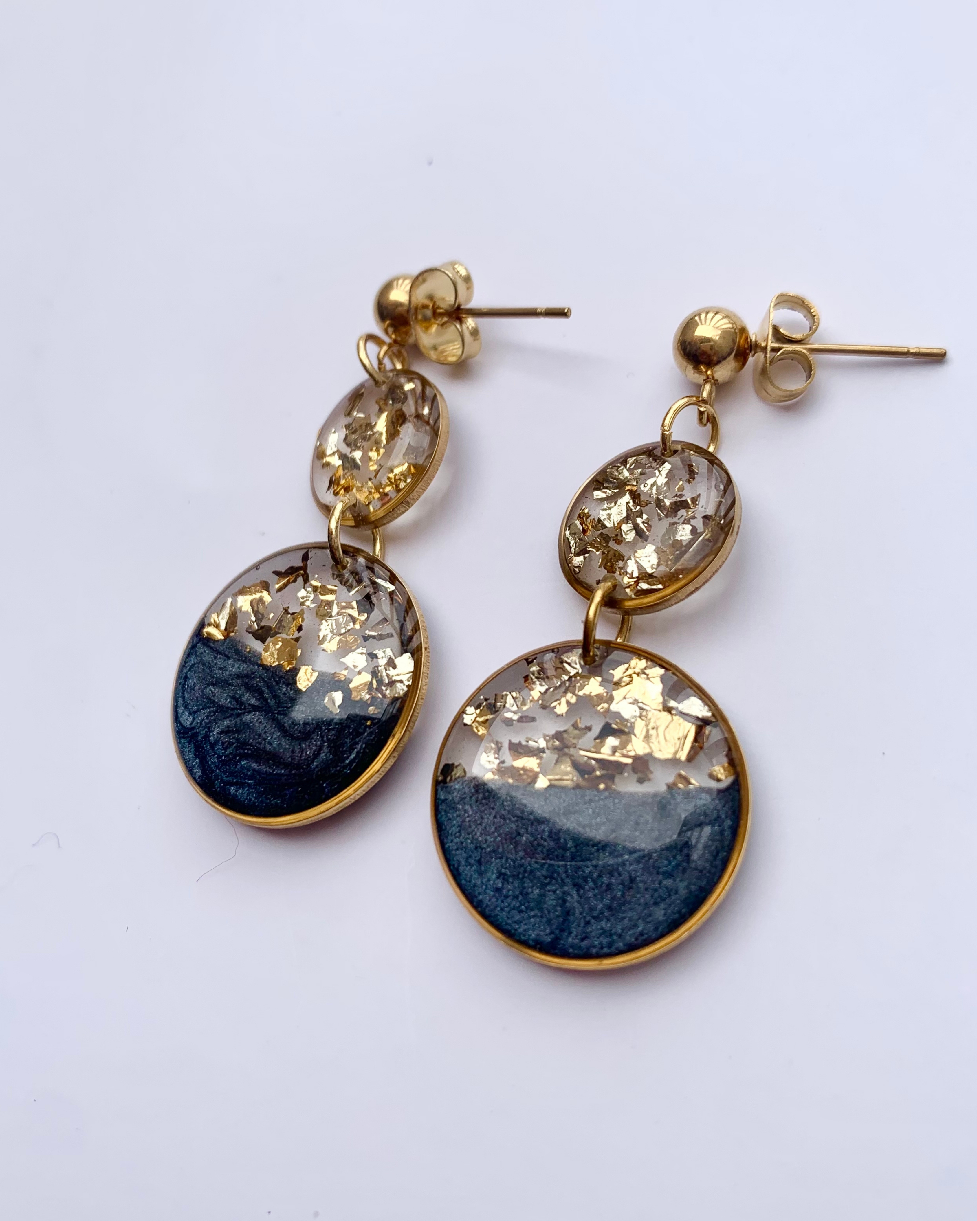 Una lujosa combinación de negro intenso, copos dorados brillantes y un elegante diseño de doble gota