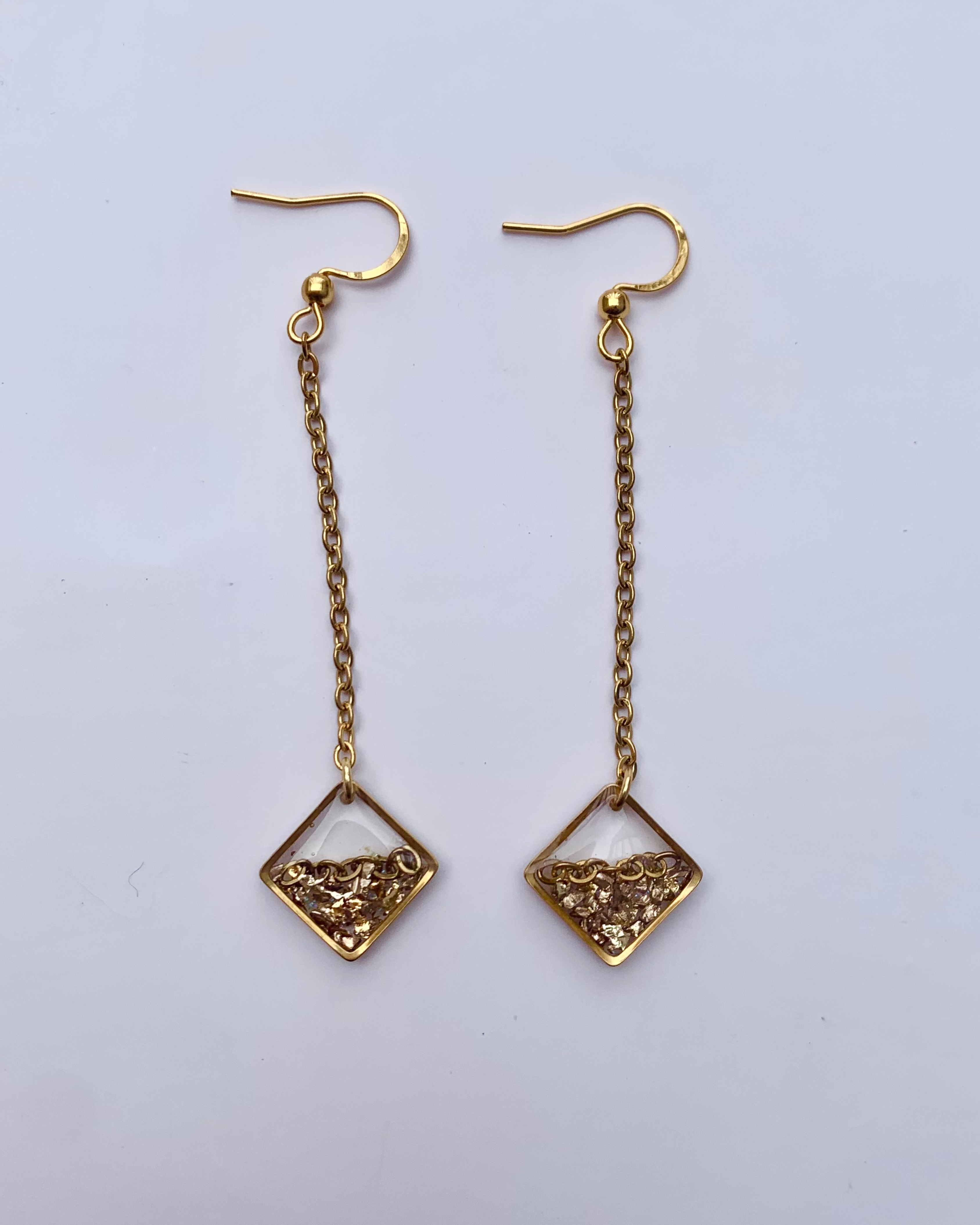 Aretes con piedras doradas, una elegante cadena de acero inoxidable y un diseño geométrico moderno