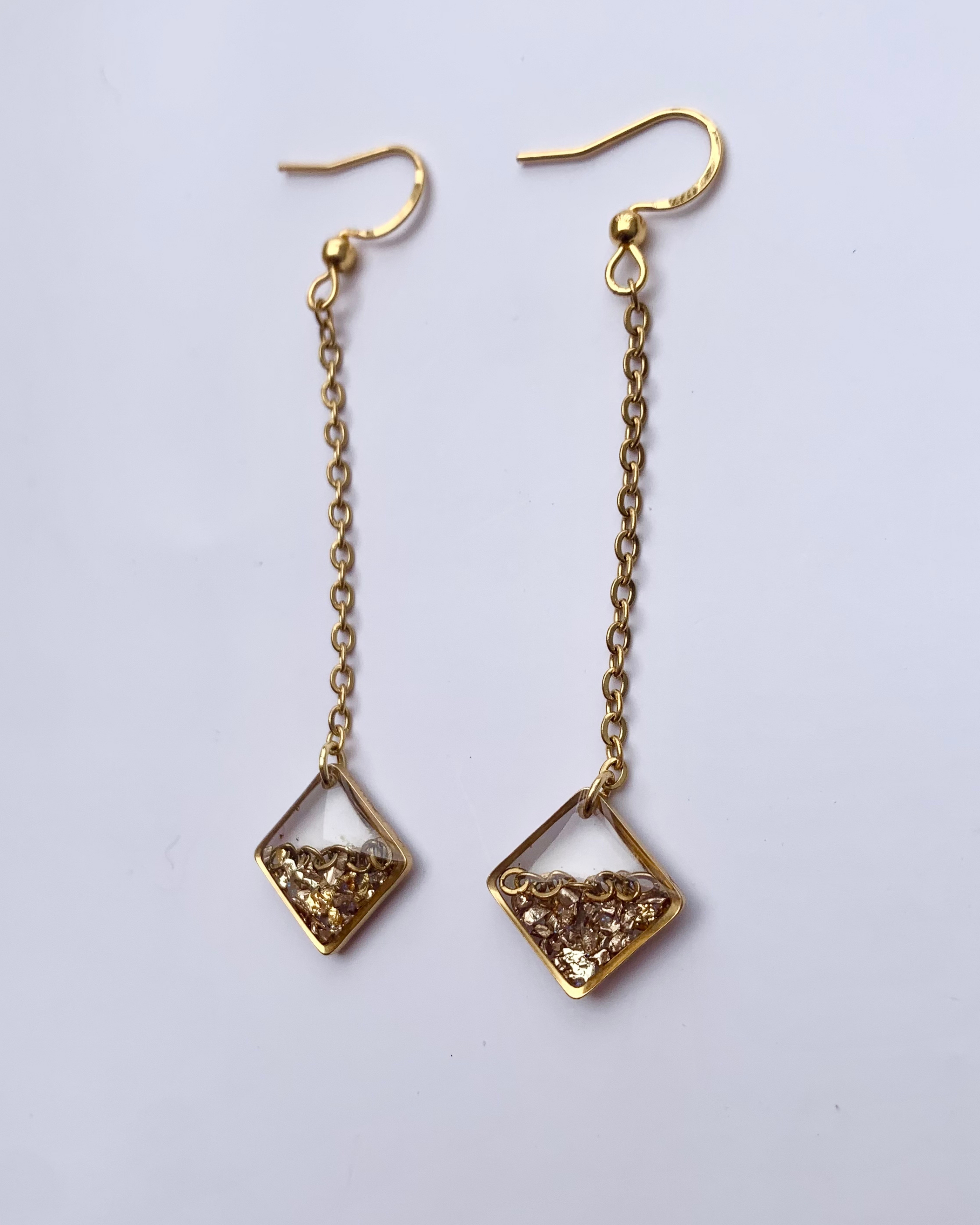 Aretes con piedras doradas, una elegante cadena de acero inoxidable y un diseño geométrico moderno