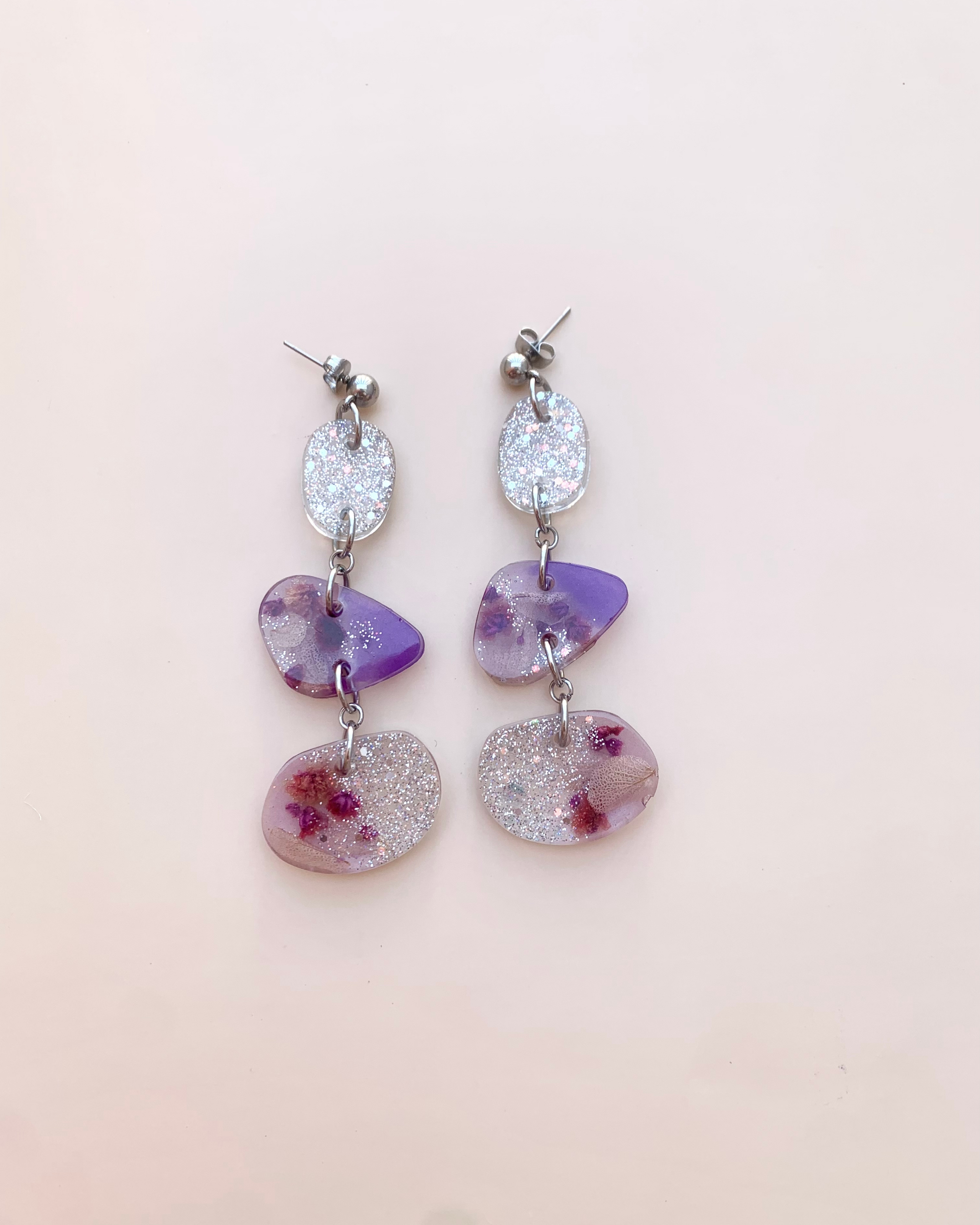 Pendientes de color morado y brillos plateados con flor