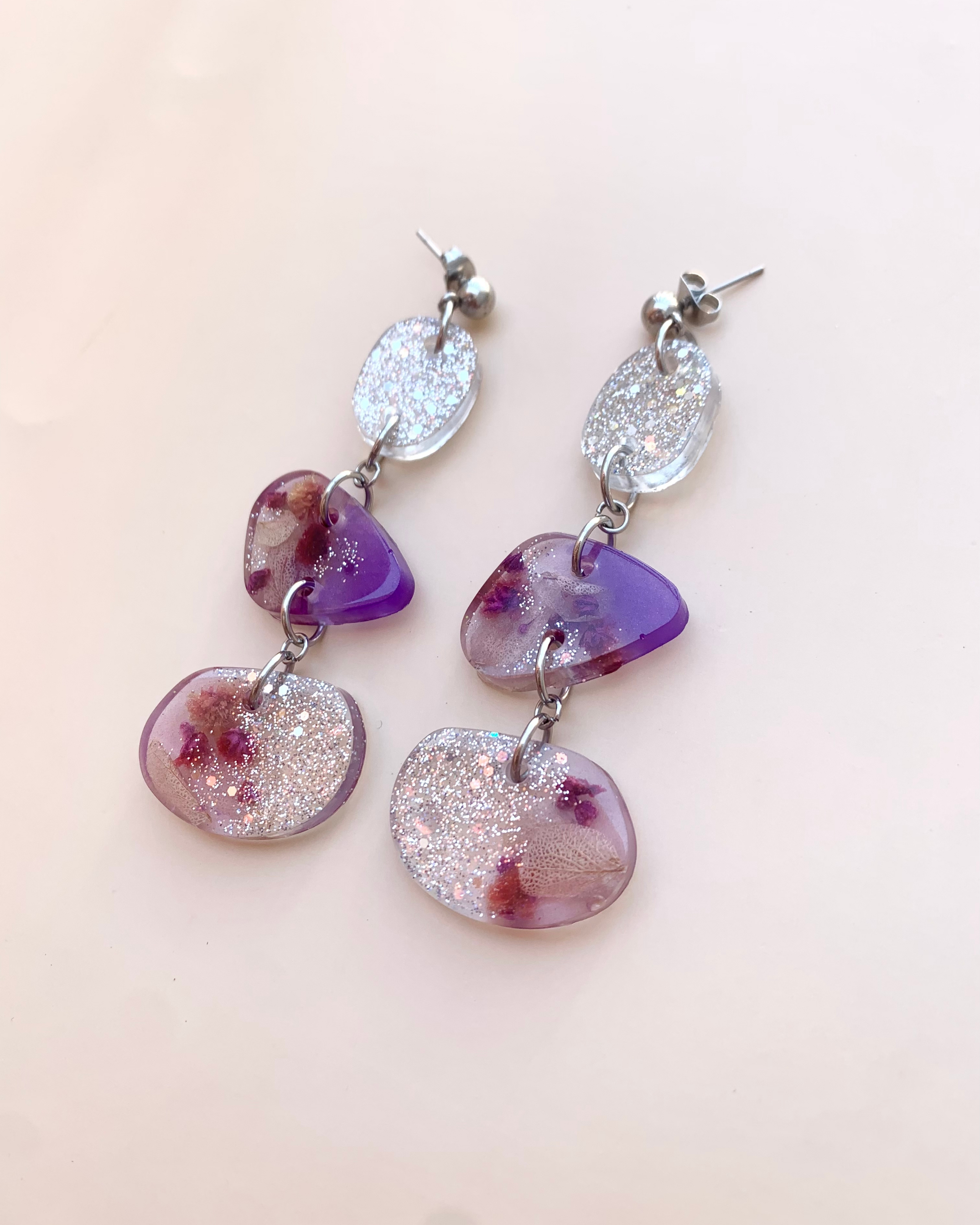 Pendientes de color morado y brillos plateados con flor