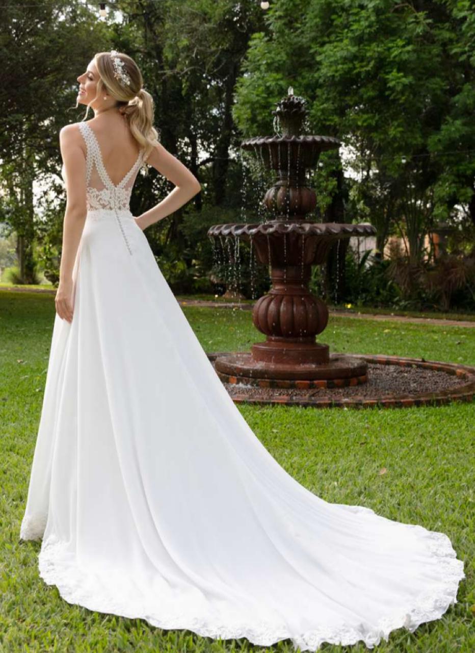 Vestido noiva fluído em musseline branco natural, apresenta ampla saia godê finalizada com barrado aplicado em renda fio de seda.