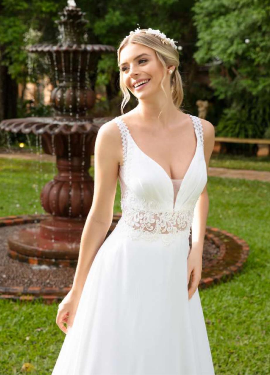 Vestido noiva fluído em musseline branco natural, apresenta ampla saia godê finalizada com barrado aplicado em renda fio de seda.