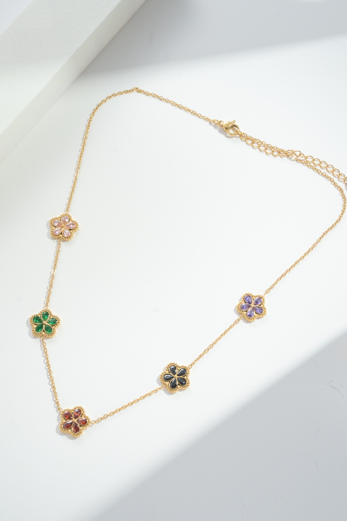 Collier doré, en acier inoxydable, qui présente des fleurs serties de cristaux colorés
