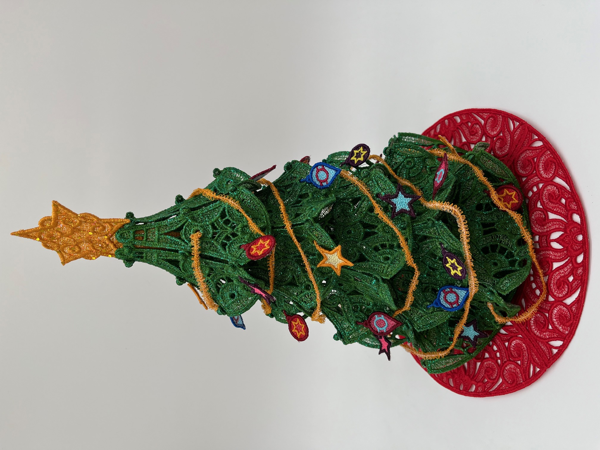 Geborduurde kerstboom met kleine ornamentjes en kerstslinger