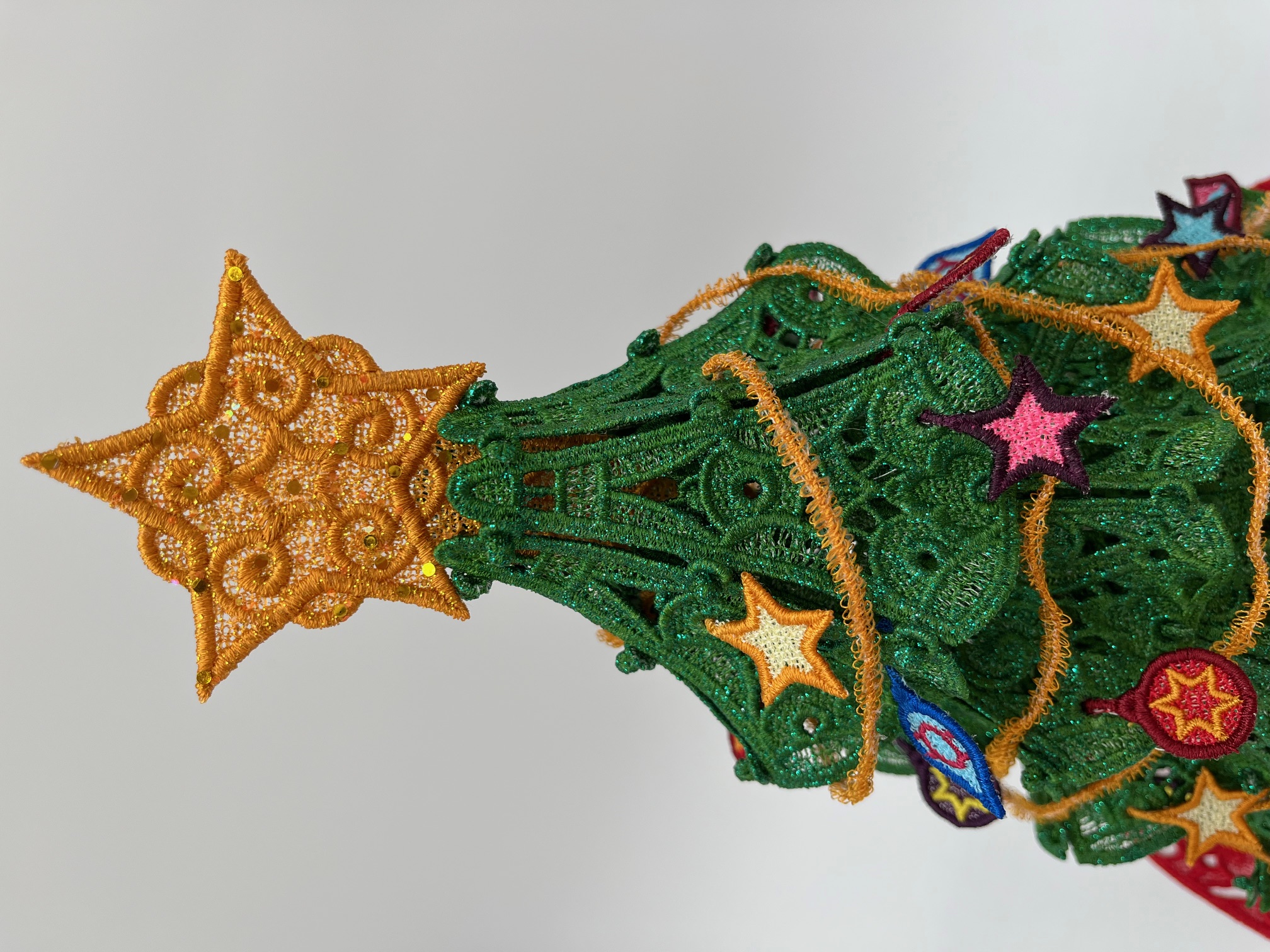 Geborduurde kerstboom met kleine ornamentjes en kerstslinger