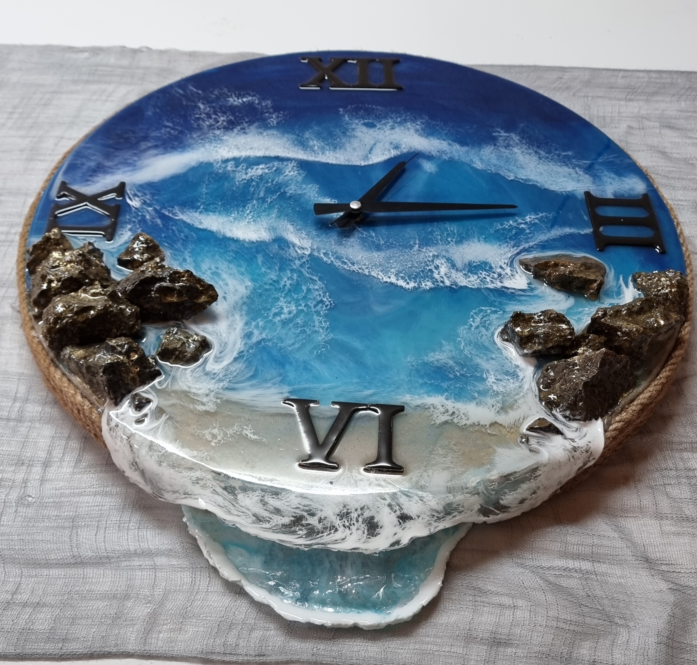 Sea-themed epoxy-resin coated clock featuring a sandy beach surrounded by rocks. Diameter: 50 cm.