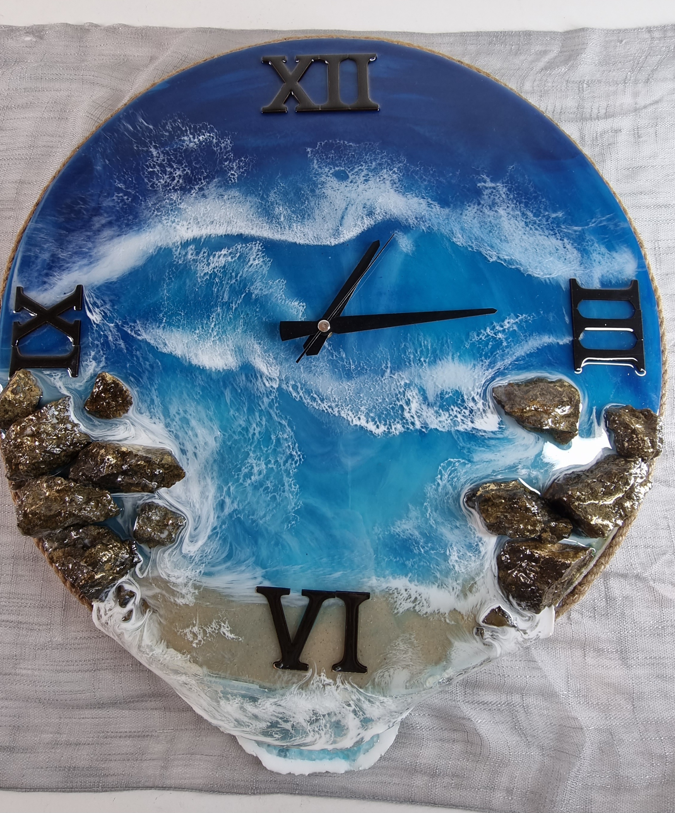 Sea-themed epoxy-resin coated clock featuring a sandy beach surrounded by rocks. Diameter: 50 cm.