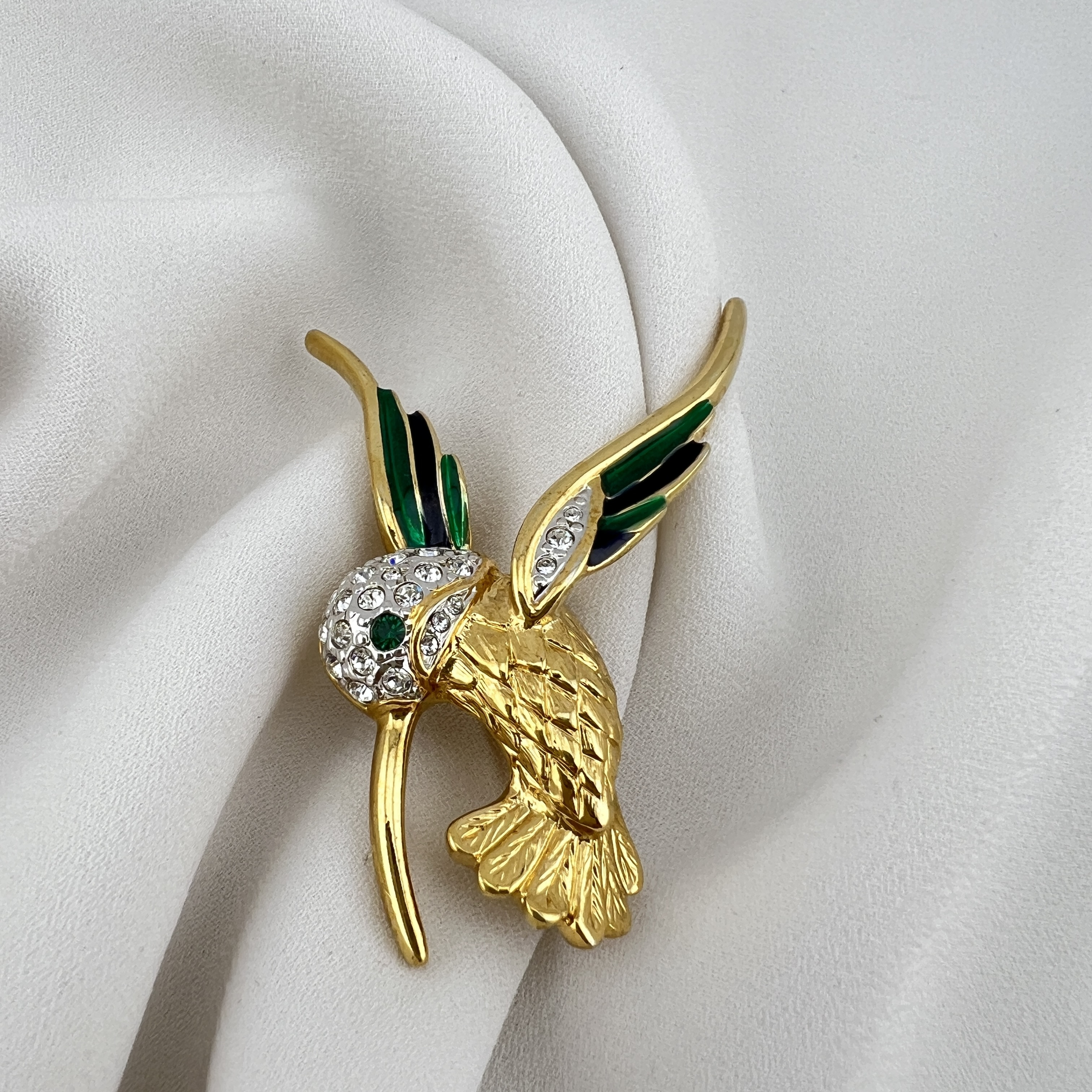 Vintažinė kolibrio sagė – smaragdinis spindesys ir judesio elegancija