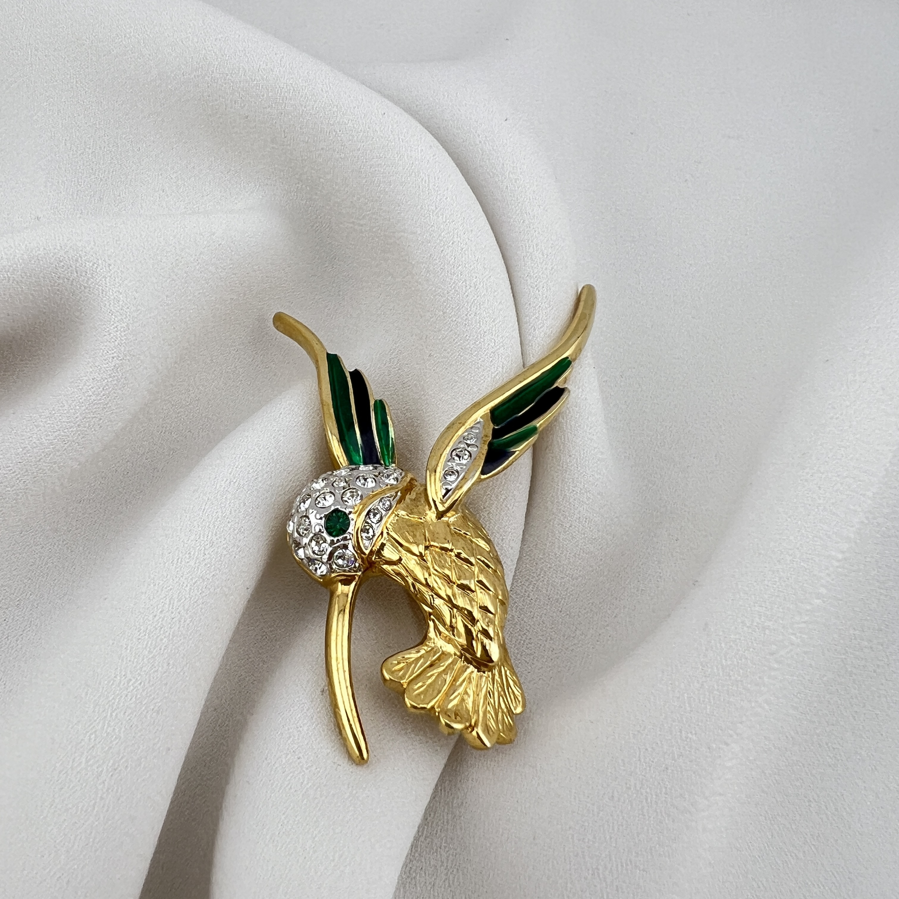 Vintažinė kolibrio sagė – smaragdinis spindesys ir judesio elegancija