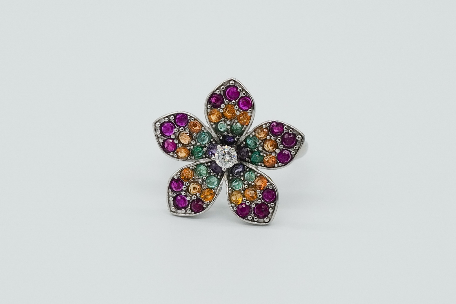 Anillo en forma de flor con esmeraldas, rubíes, zafiros naranjas y una gran moisanita
