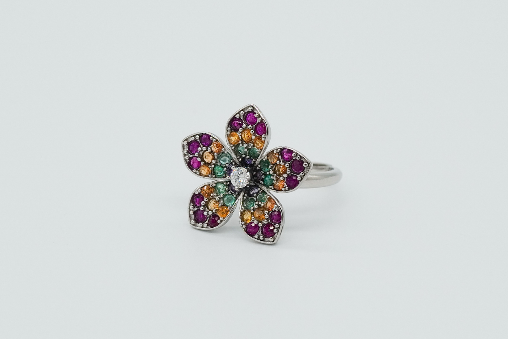 Anillo en forma de flor con esmeraldas, rubíes, zafiros naranjas y una gran moisanita