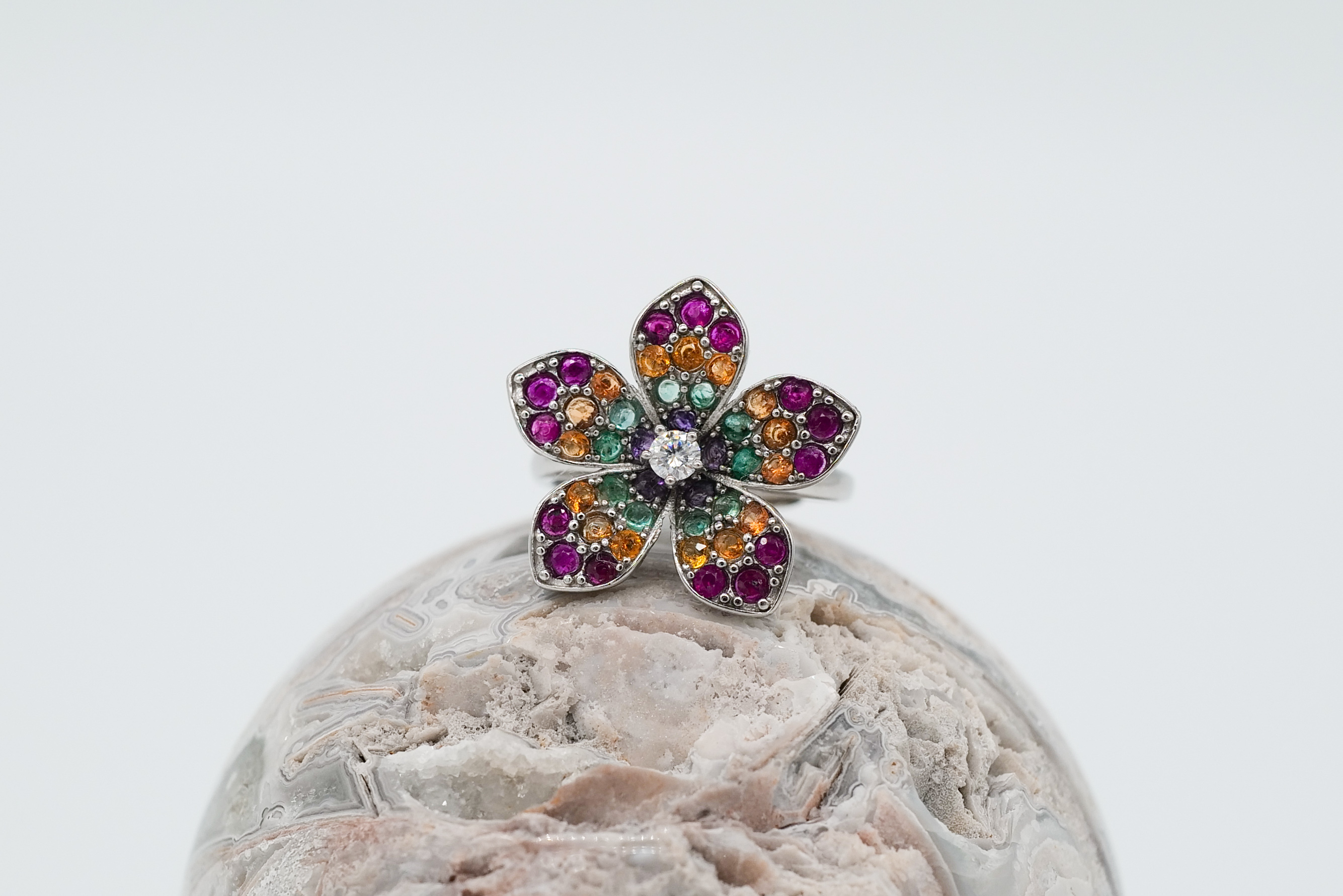 Anillo en forma de flor con esmeraldas, rubíes, zafiros naranjas y una gran moisanita