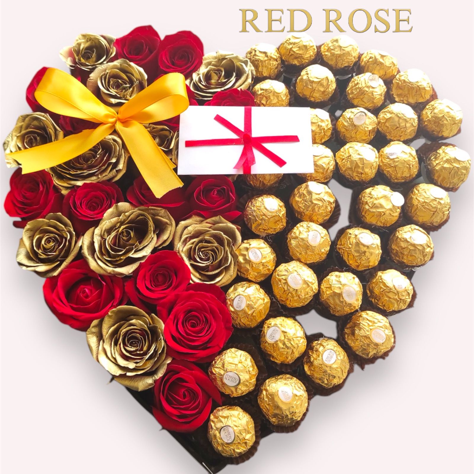 Cajita con forma de corazón con chocolates, rosas rojas y doradas con un moño dorado.