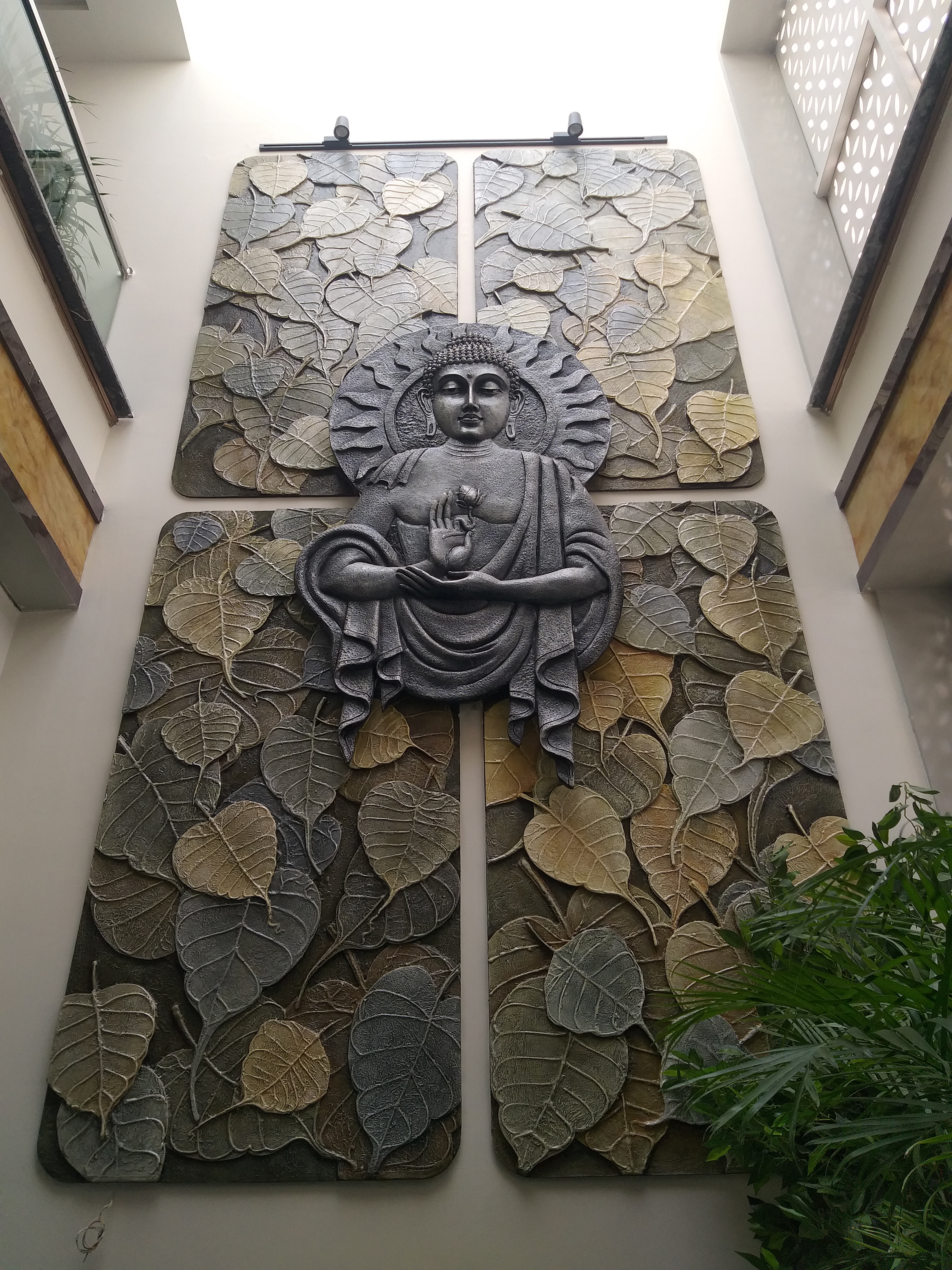 16ft x 7ft Buddha Fiber Mural on Mixed Media Backgroud with peepal leaves with Antique Grey colour finish on a double heighted wall for a Triplex villa