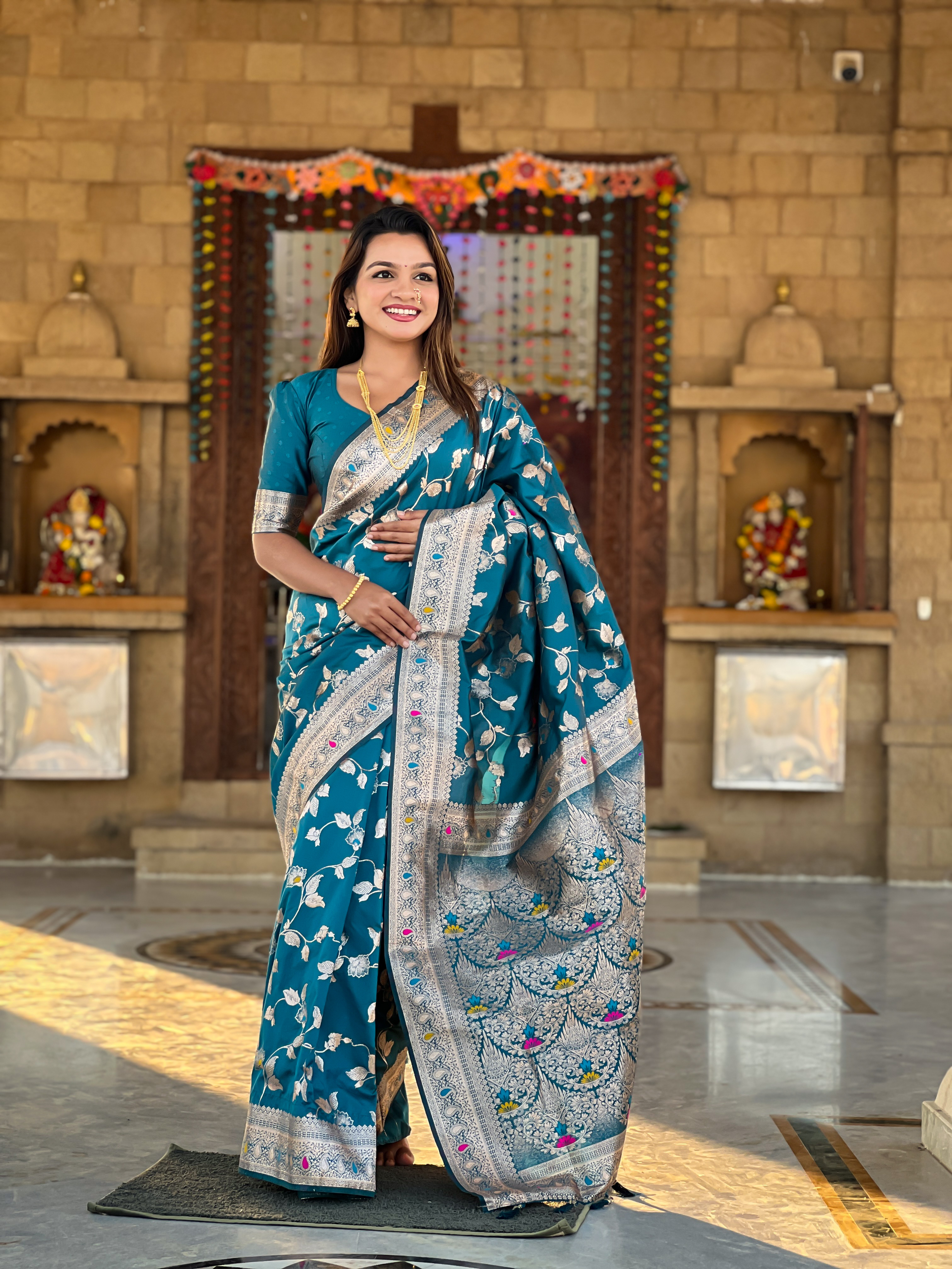Immerse yourself in the vibrant charm of this turquoise blue Banarasi silk saree