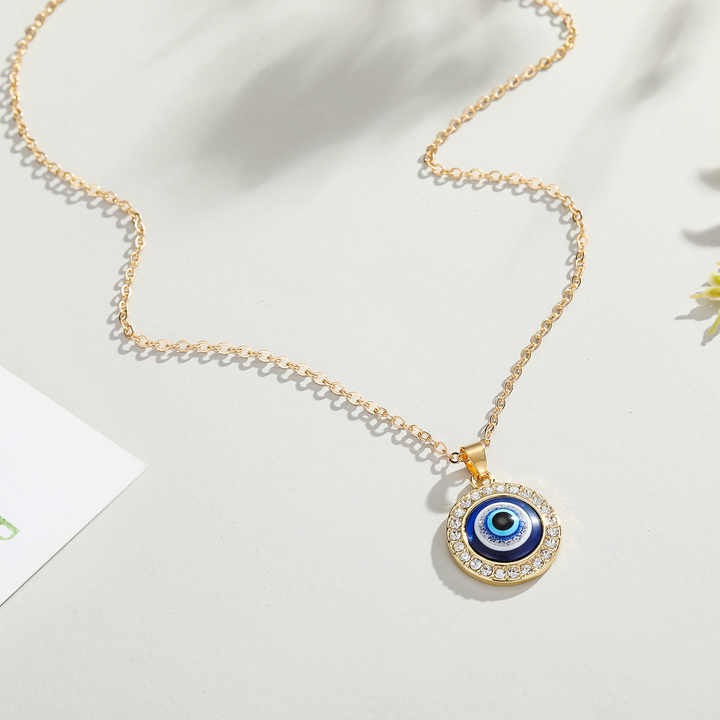 Protective blue evil eye pendant necklace with shiny diamond detail, silver link chain, pearl accent, and leather cord — a perfect stylish gift for any occasion.