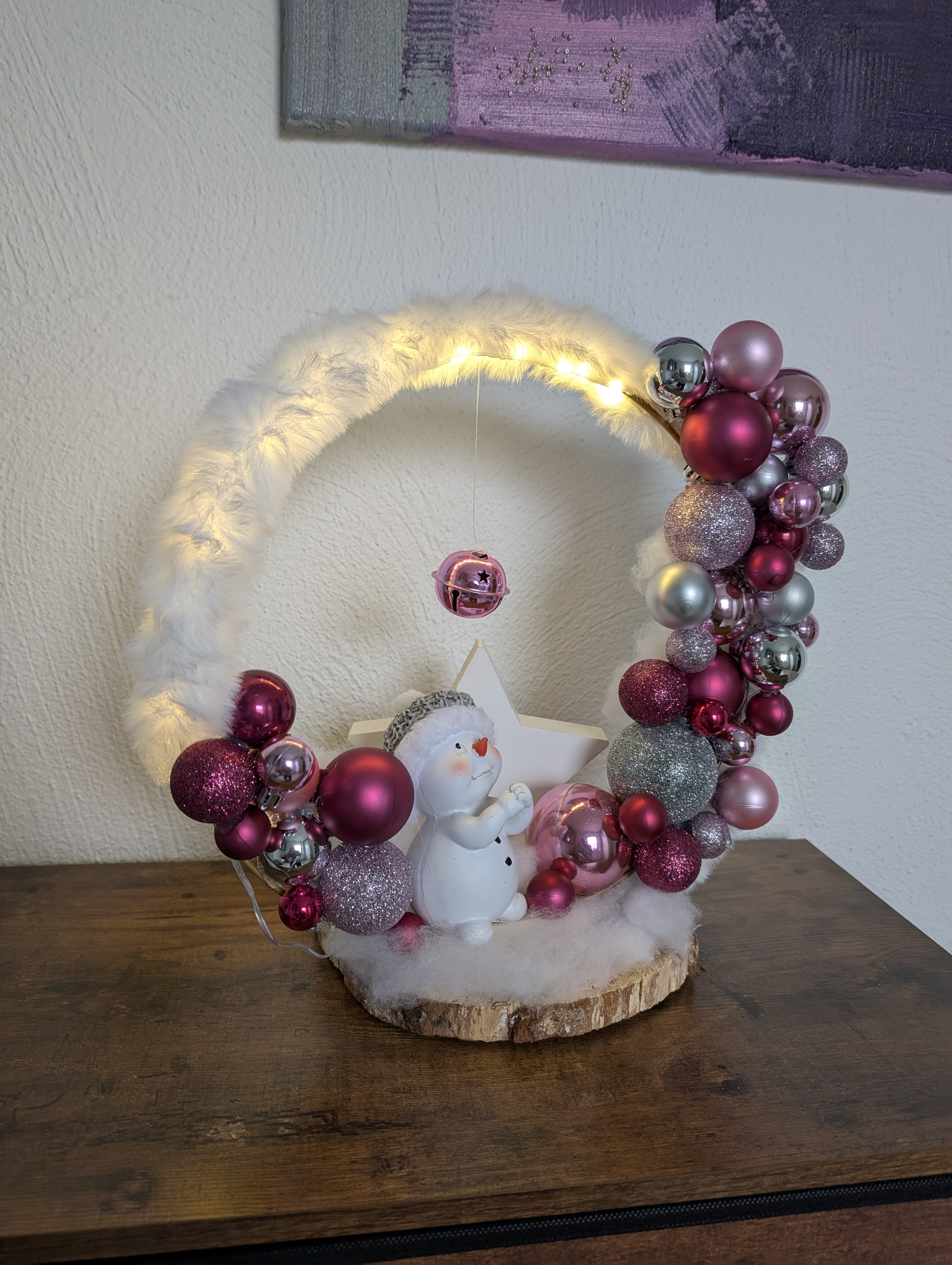 Weihnachtlicher Loop beleuchtet auf Birkenholz als Standfuß, mit Schneemann und großem Stern und Kugeln in zartem Rosa, elegantem Silber und edlem Violett