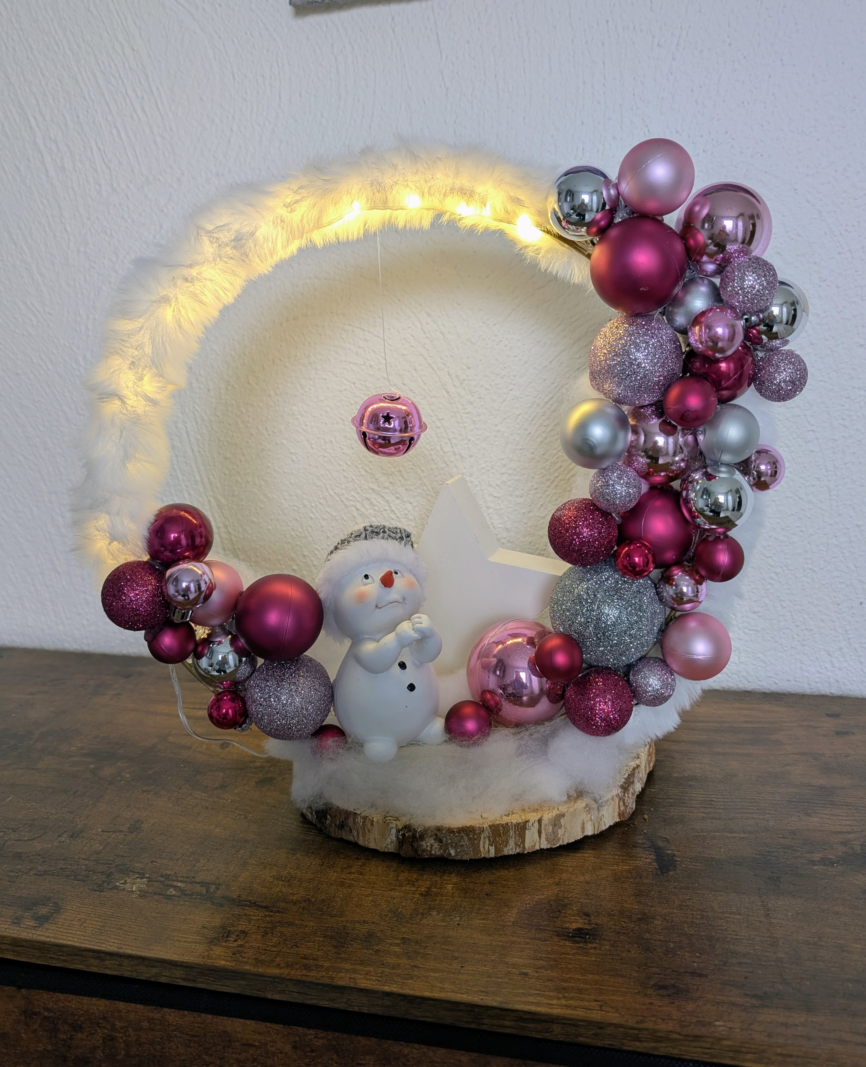 Weihnachtlicher Loop beleuchtet auf Birkenholz als Standfuß, mit Schneemann und großem Stern und Kugeln in zartem Rosa, elegantem Silber und edlem Violett