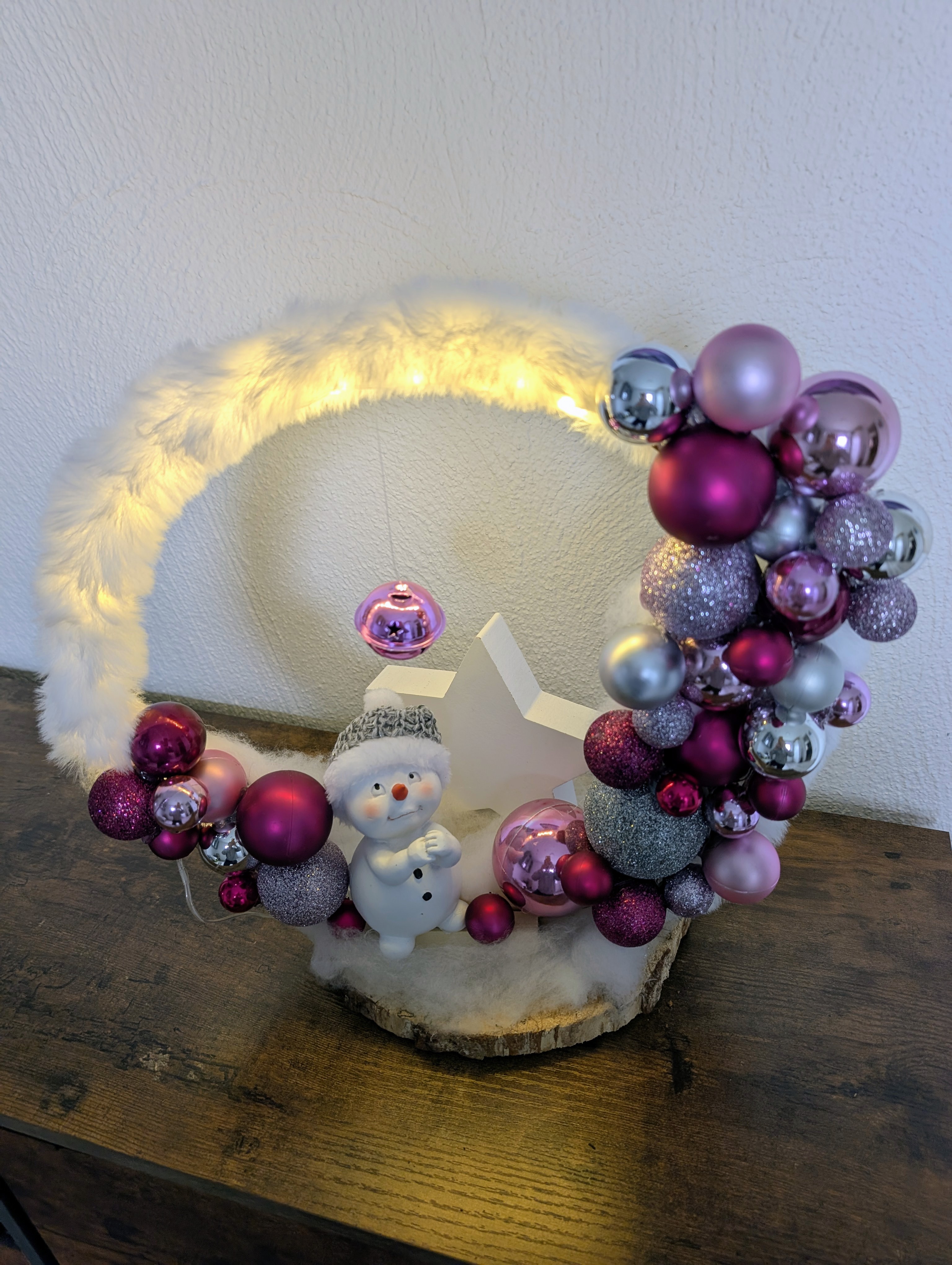 Weihnachtlicher Loop beleuchtet auf Birkenholz als Standfuß, mit Schneemann und großem Stern und Kugeln in zartem Rosa, elegantem Silber und edlem Violett
