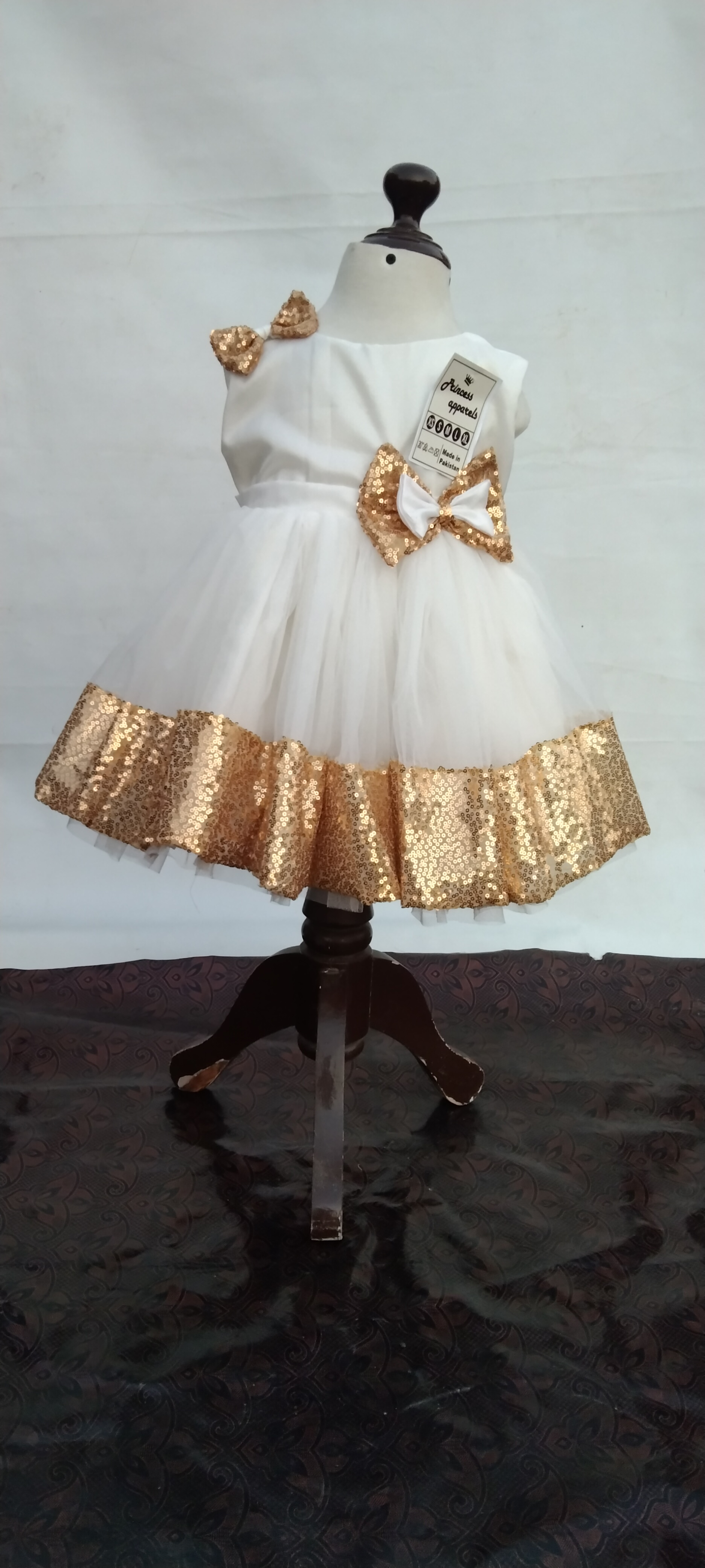 Golden Hour Glam, handcrafted party dress for baby girls features white silk and net, gold sequins, delicate bows, and a multi-layered skirt for graceful movement.