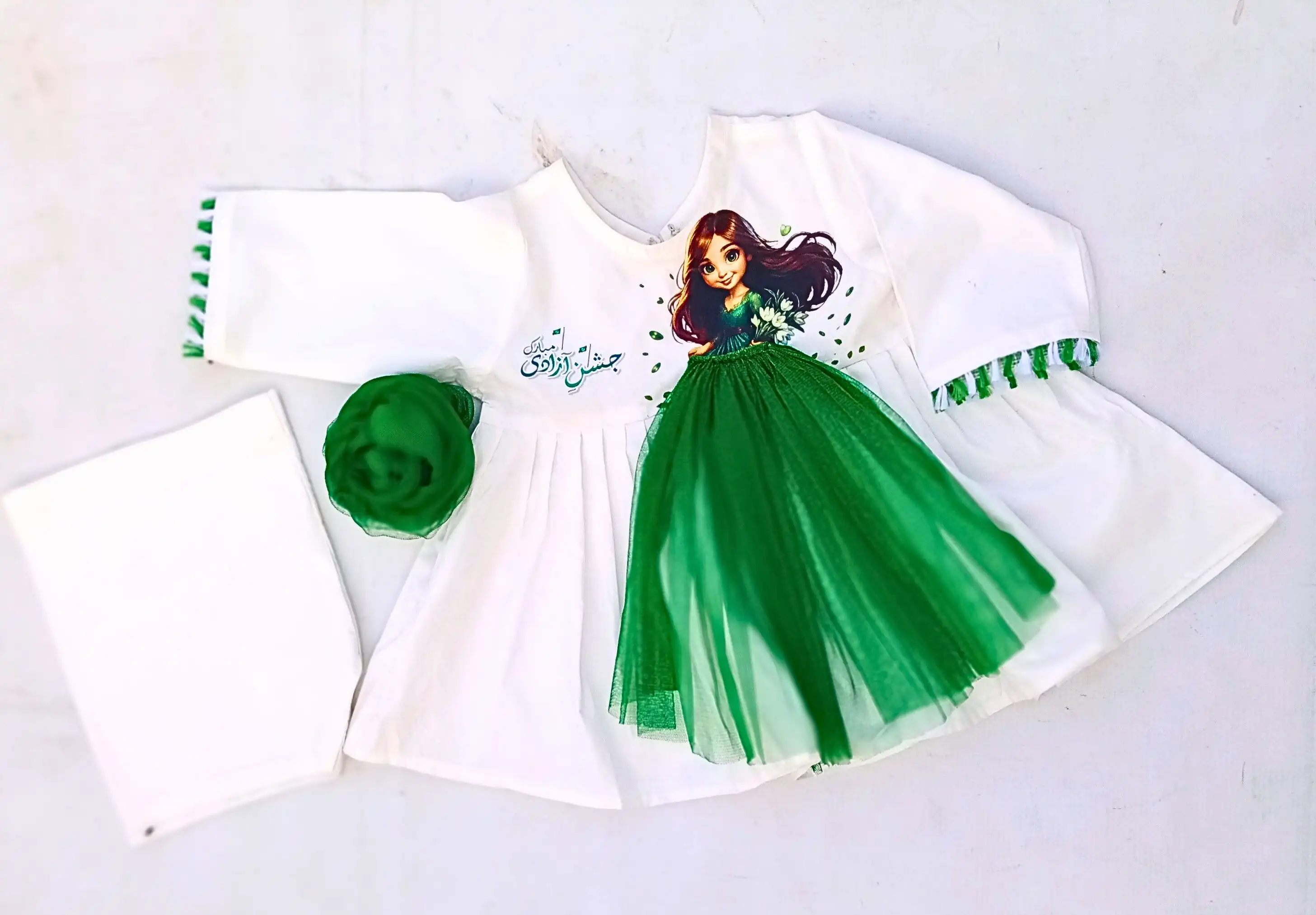 Doll of Independence A white baby or toddler dress with a green doll graphic and green accents, for Pakistan Independence Day