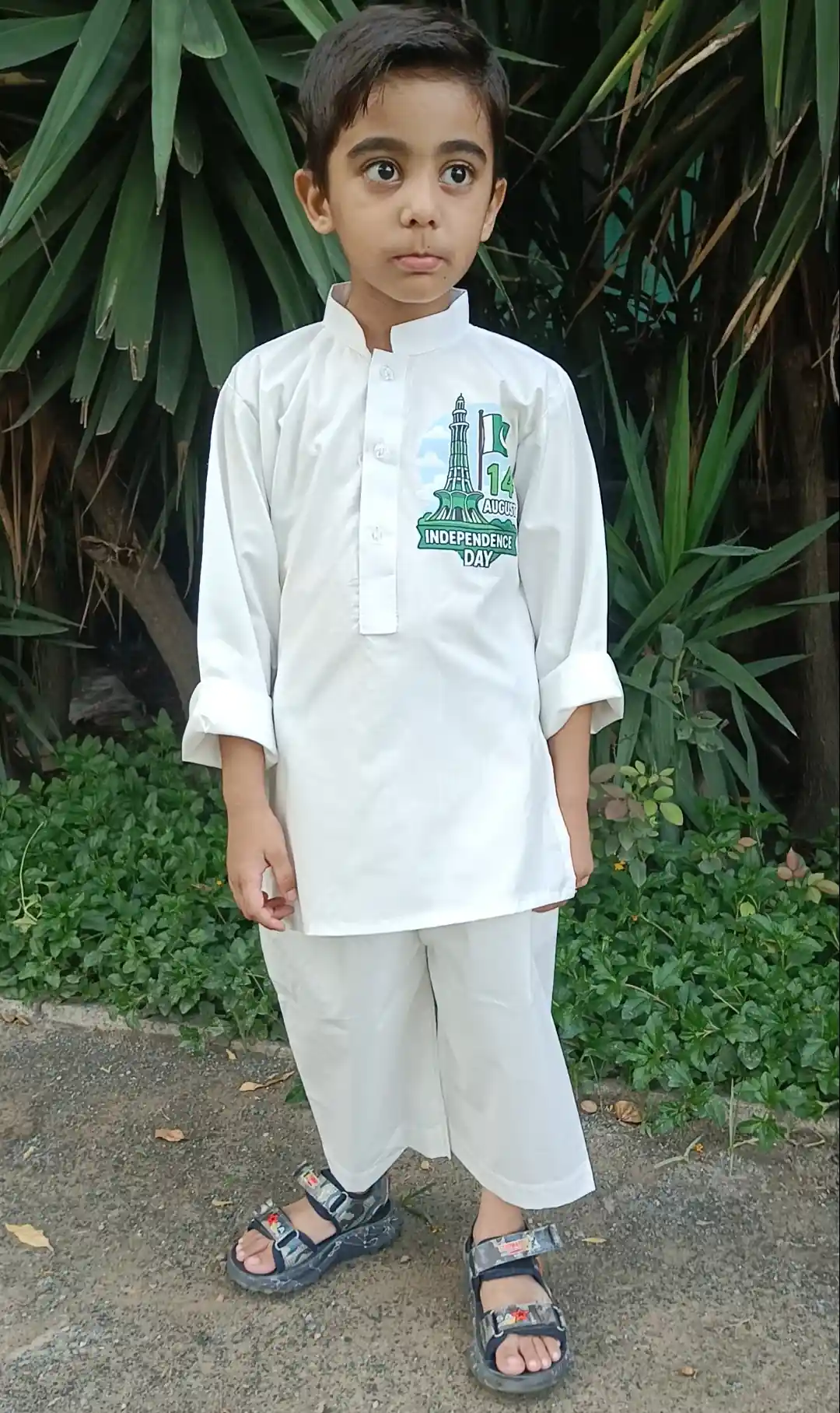Freedom Festival Cotton Shalwar Qameez A young Pakistani boy in a white shalwar qameez with an Independence Day graphic.