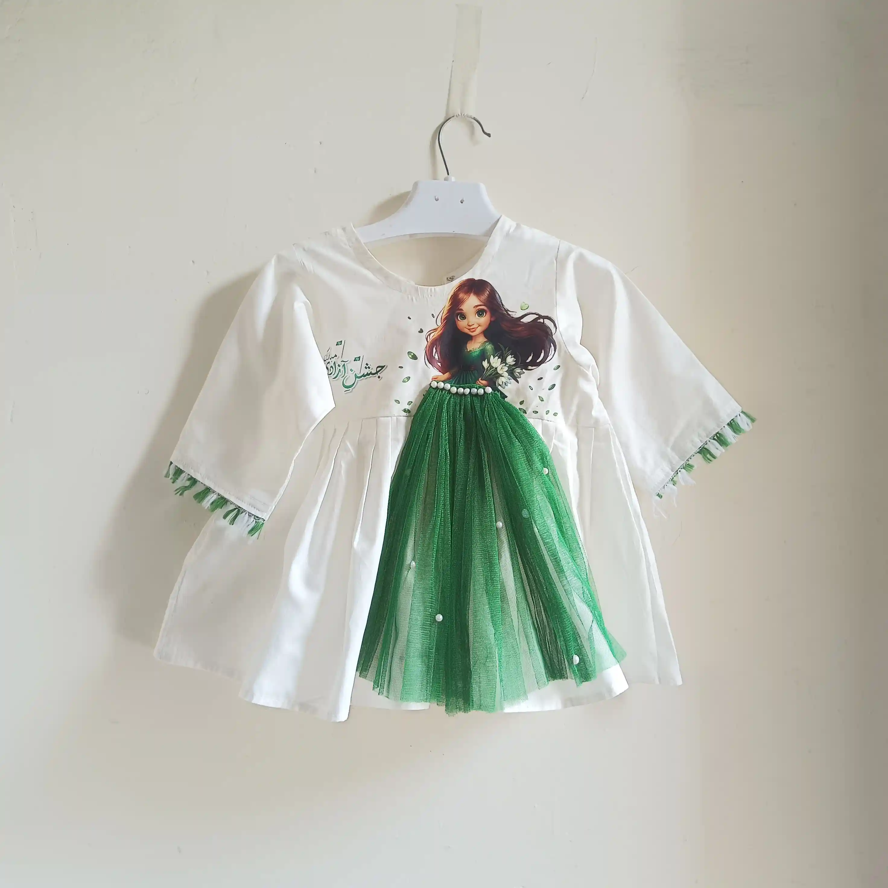 Doll of Independence A white baby or toddler dress with a green doll graphic and green accents, for Pakistan Independence Day