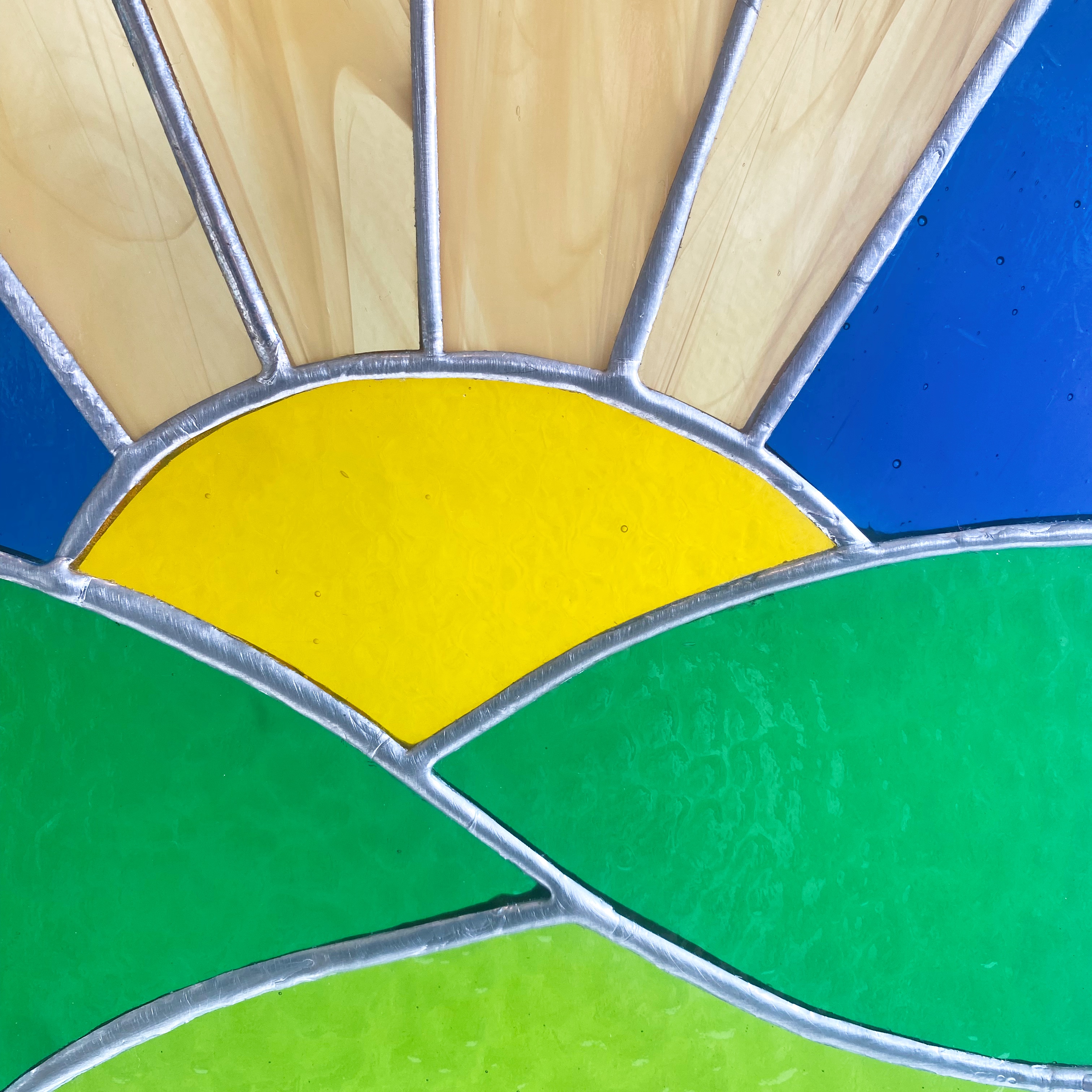 Stained glass sunrise over green fields.