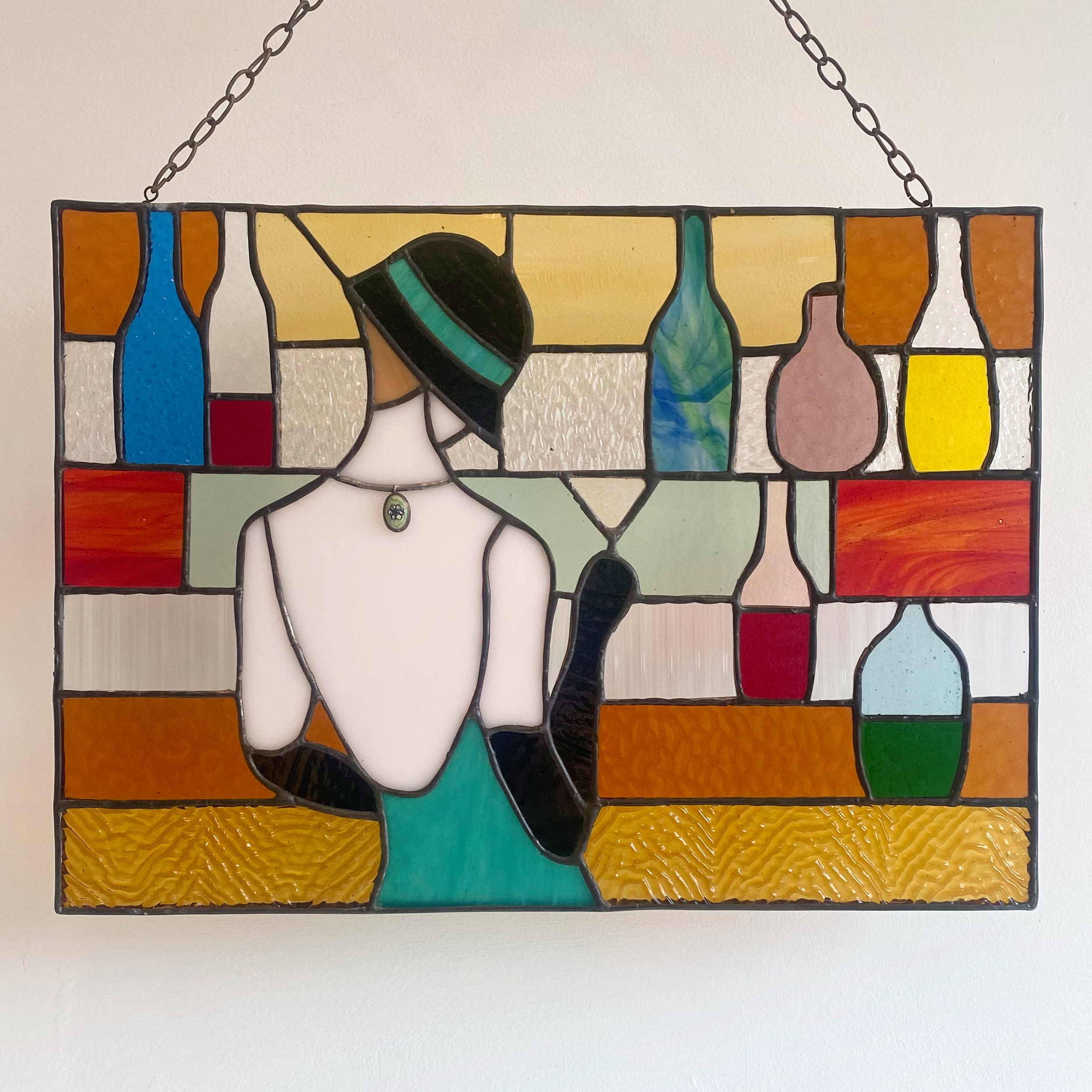 Contemporary stained glass panel with a lady stood at a bar.