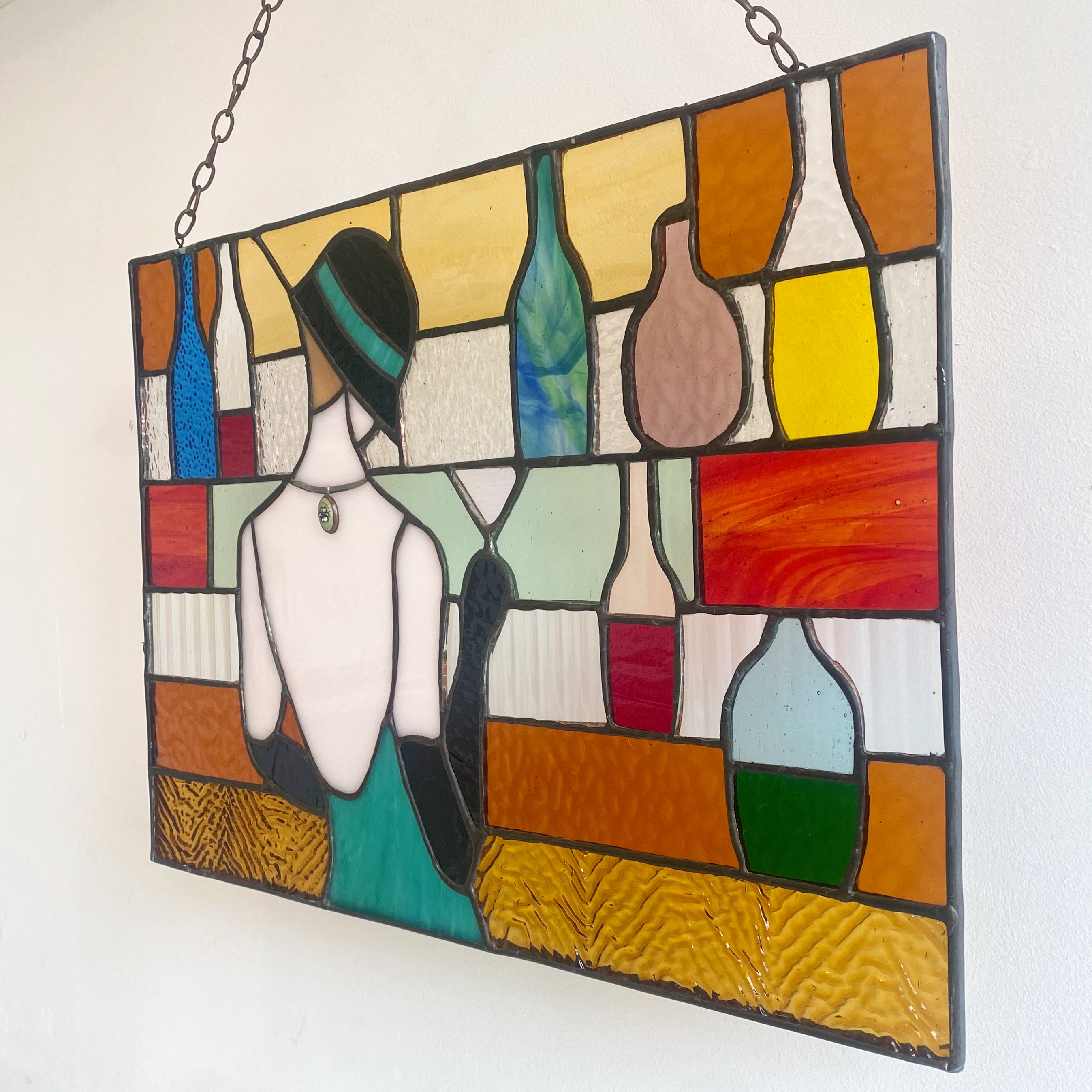 Contemporary stained glass panel with a lady stood at a bar.