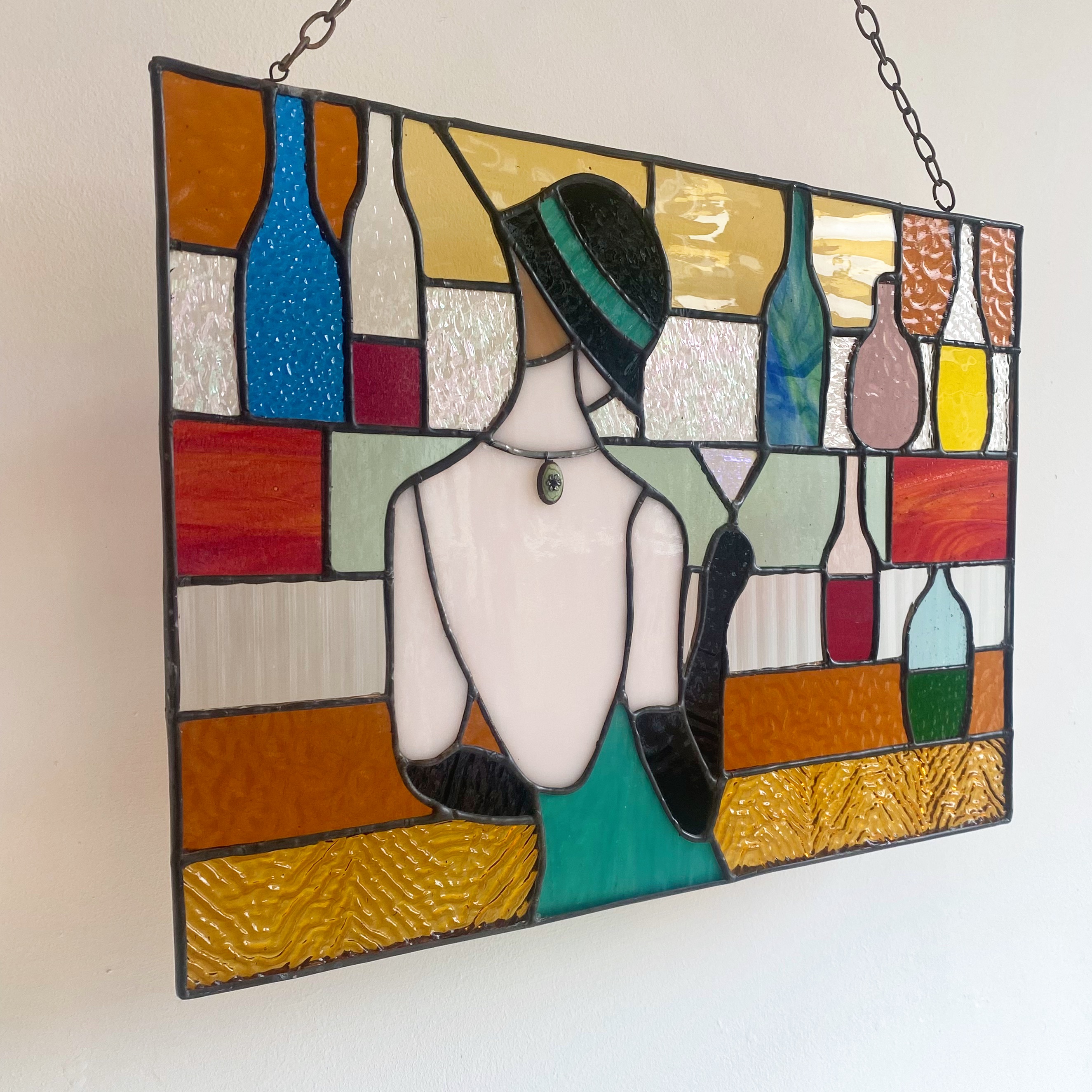 Contemporary stained glass panel with a lady stood at a bar.