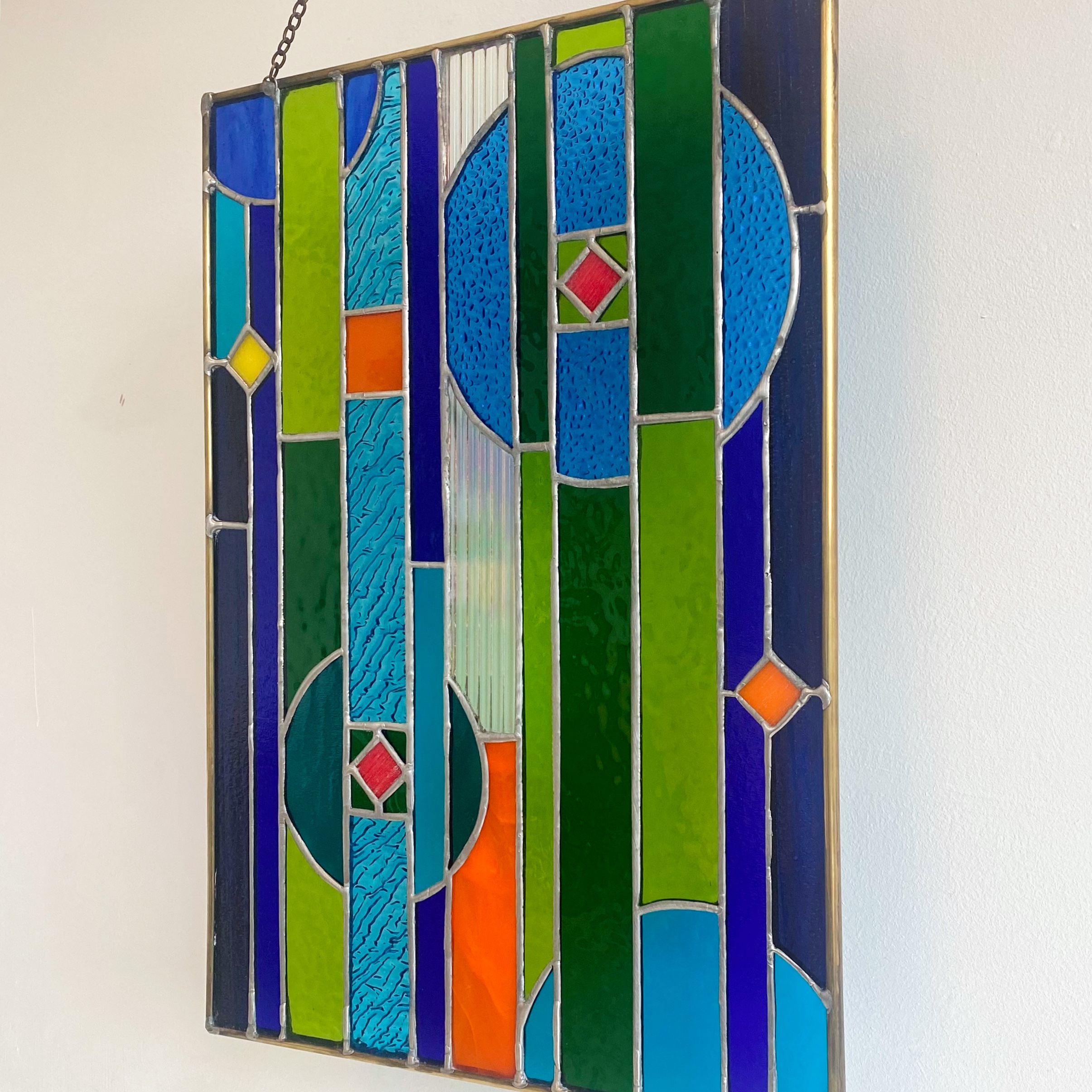 Contemporary stained glass panel in blue, green and orange.
