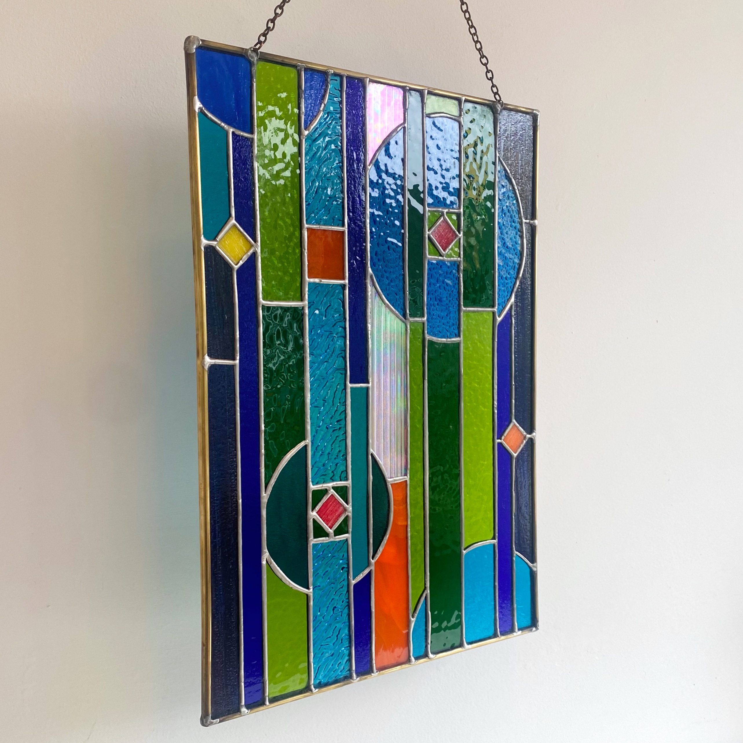 Contemporary stained glass panel in blue, green and orange.