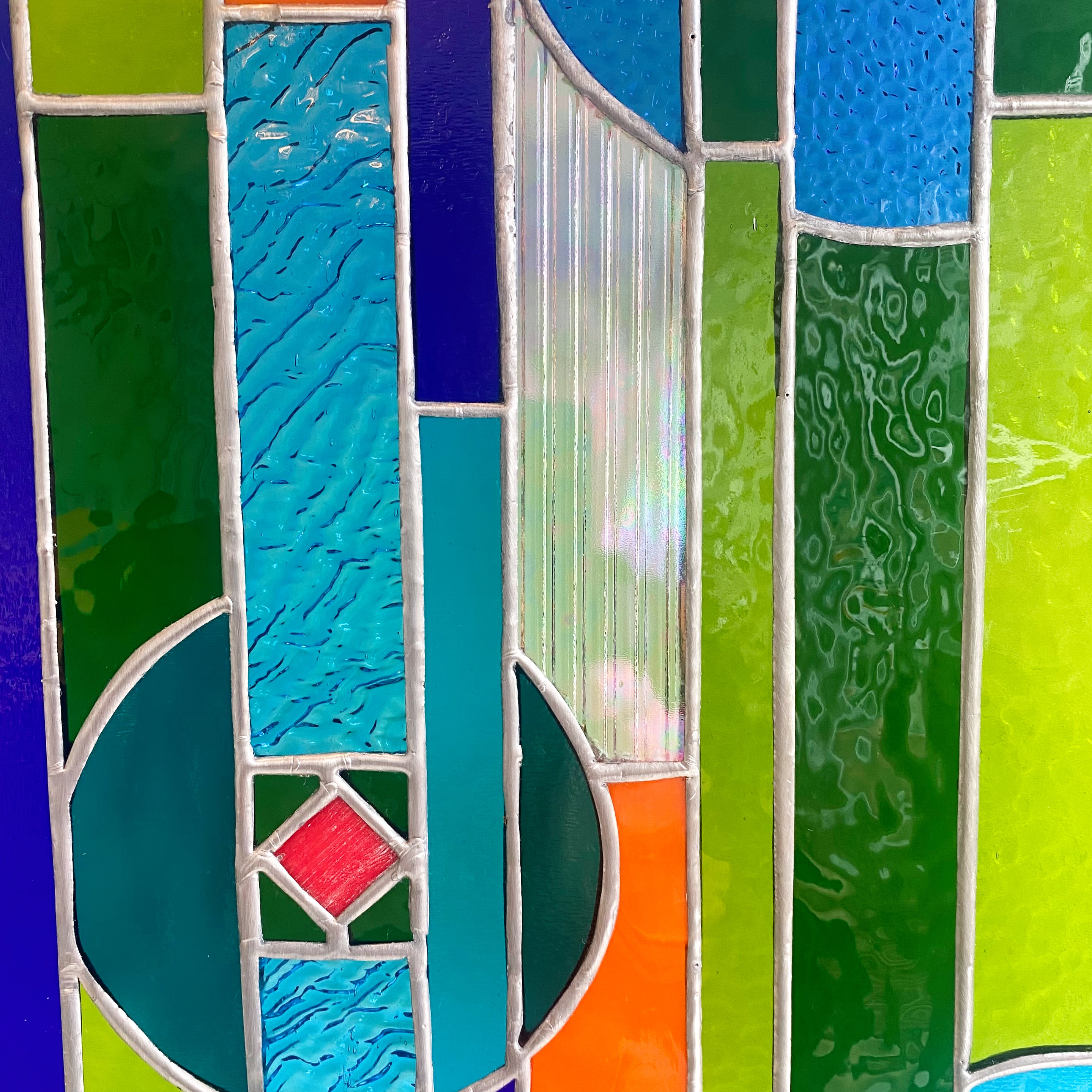 Contemporary stained glass panel in blue, green and orange.