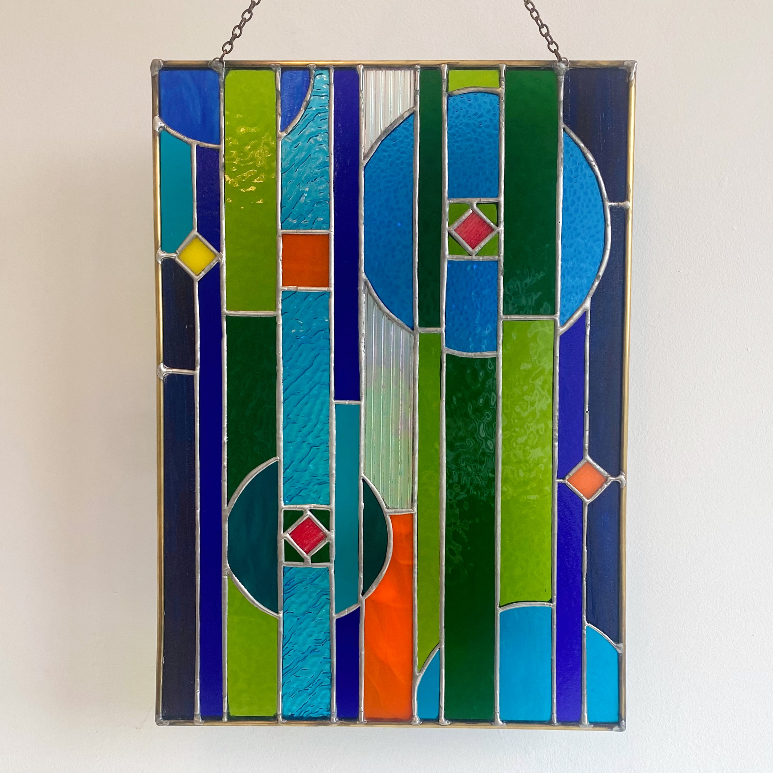 Contemporary stained glass panel in blue, green and orange.