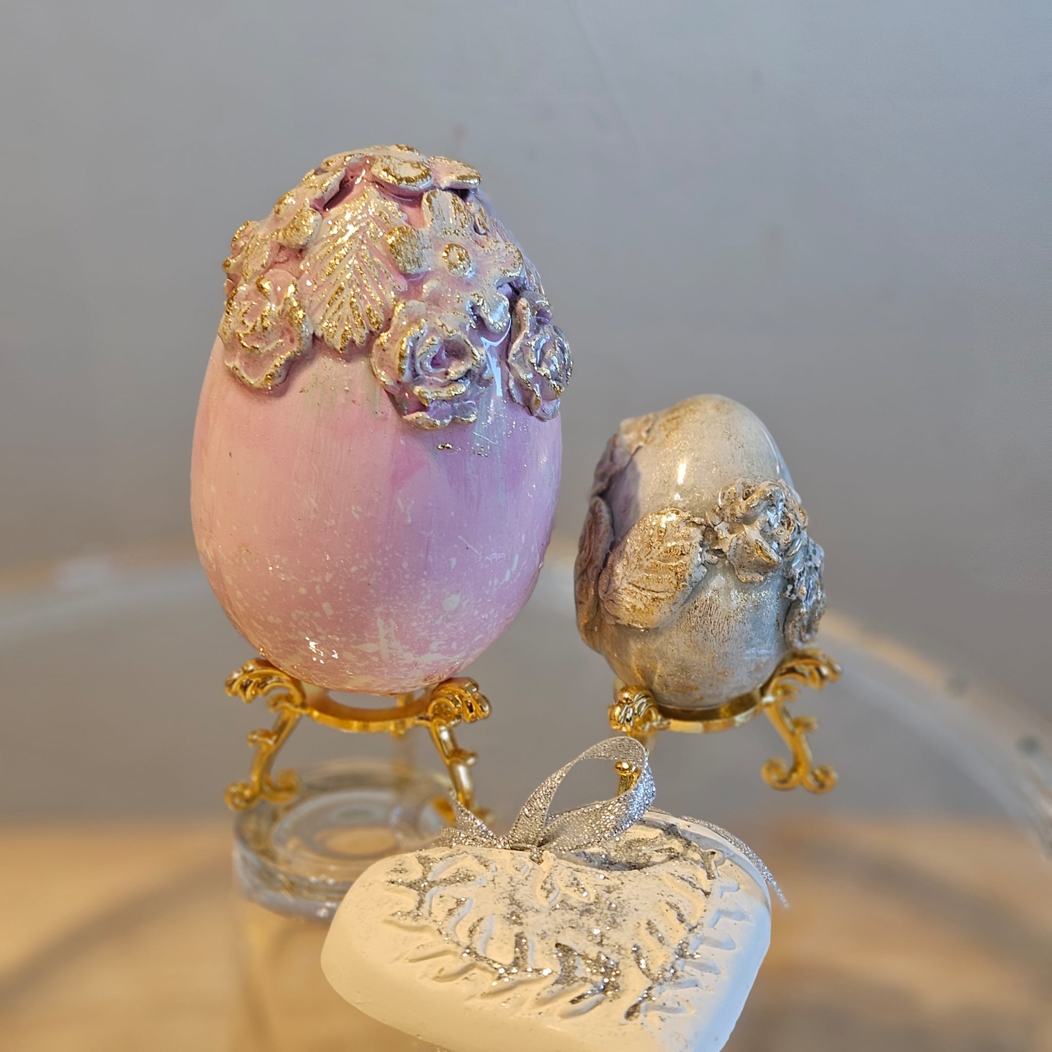 Lot de deux œufs sculptés et cœur de plâtre, supports dorés offerts