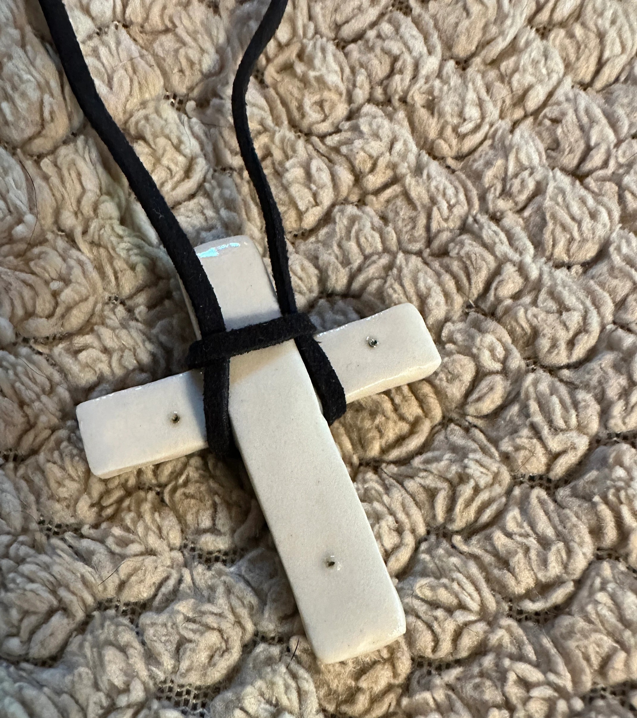 White hand made porcelain Christian cross with copper and royal blue polymer design fill on black suede cord with barrel clasp