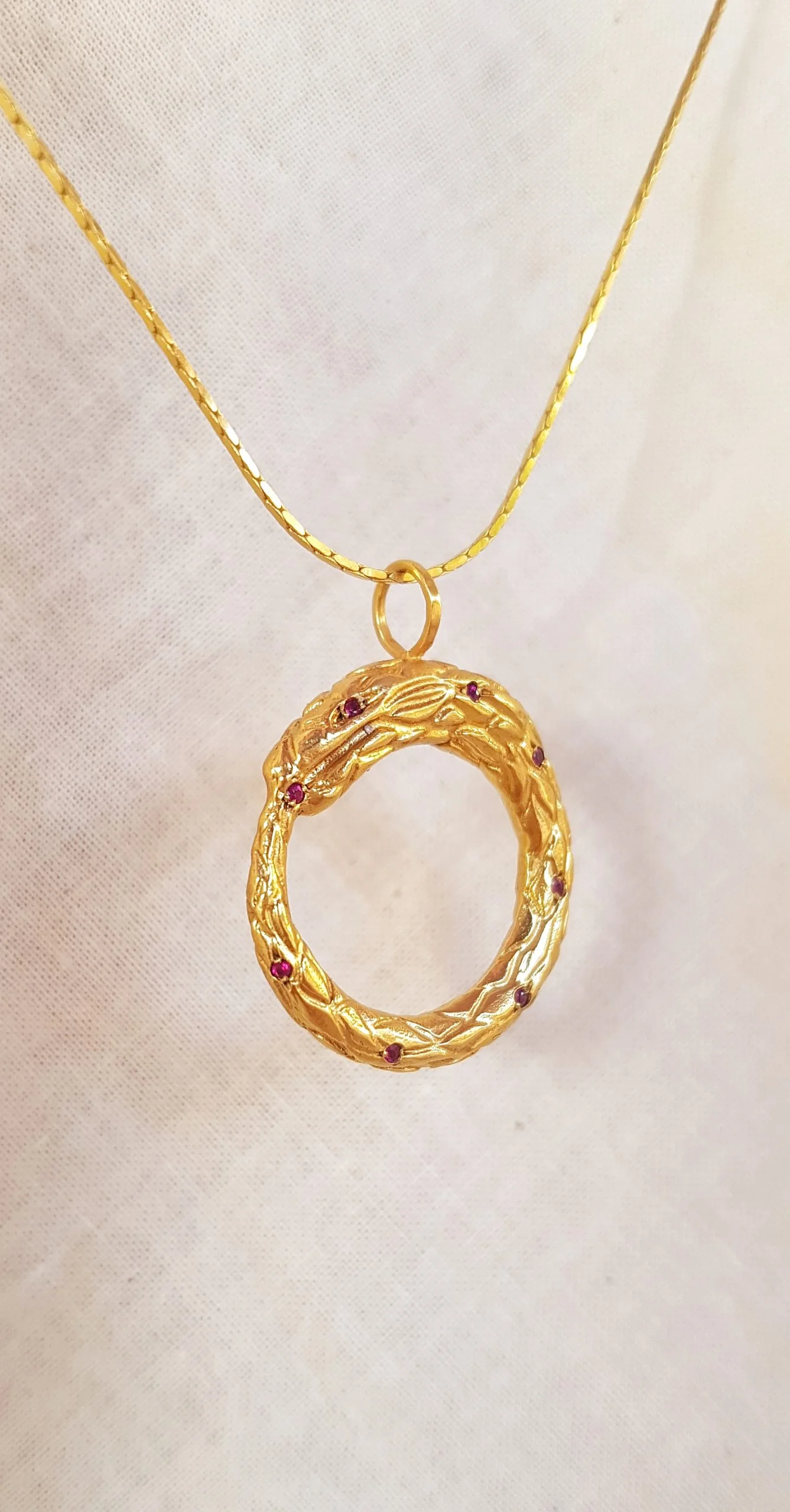 Colgante Ouroboros dorado con rubíes